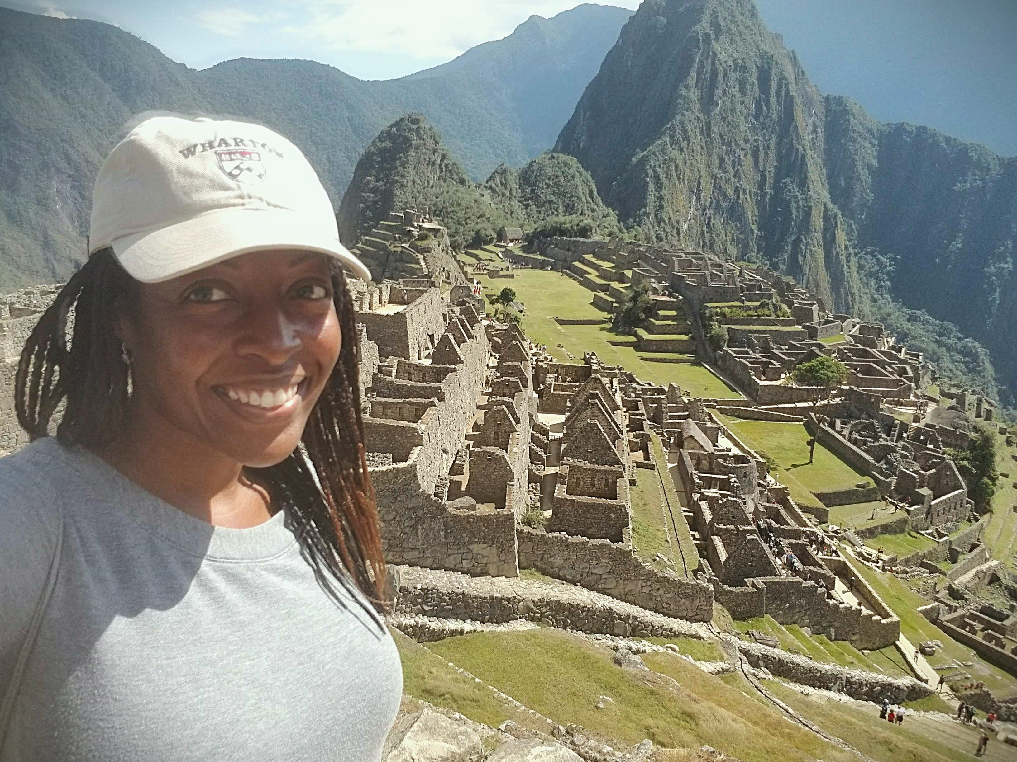 Advisor taking a selfie with the ruins of Machu Picchu on a sunny day