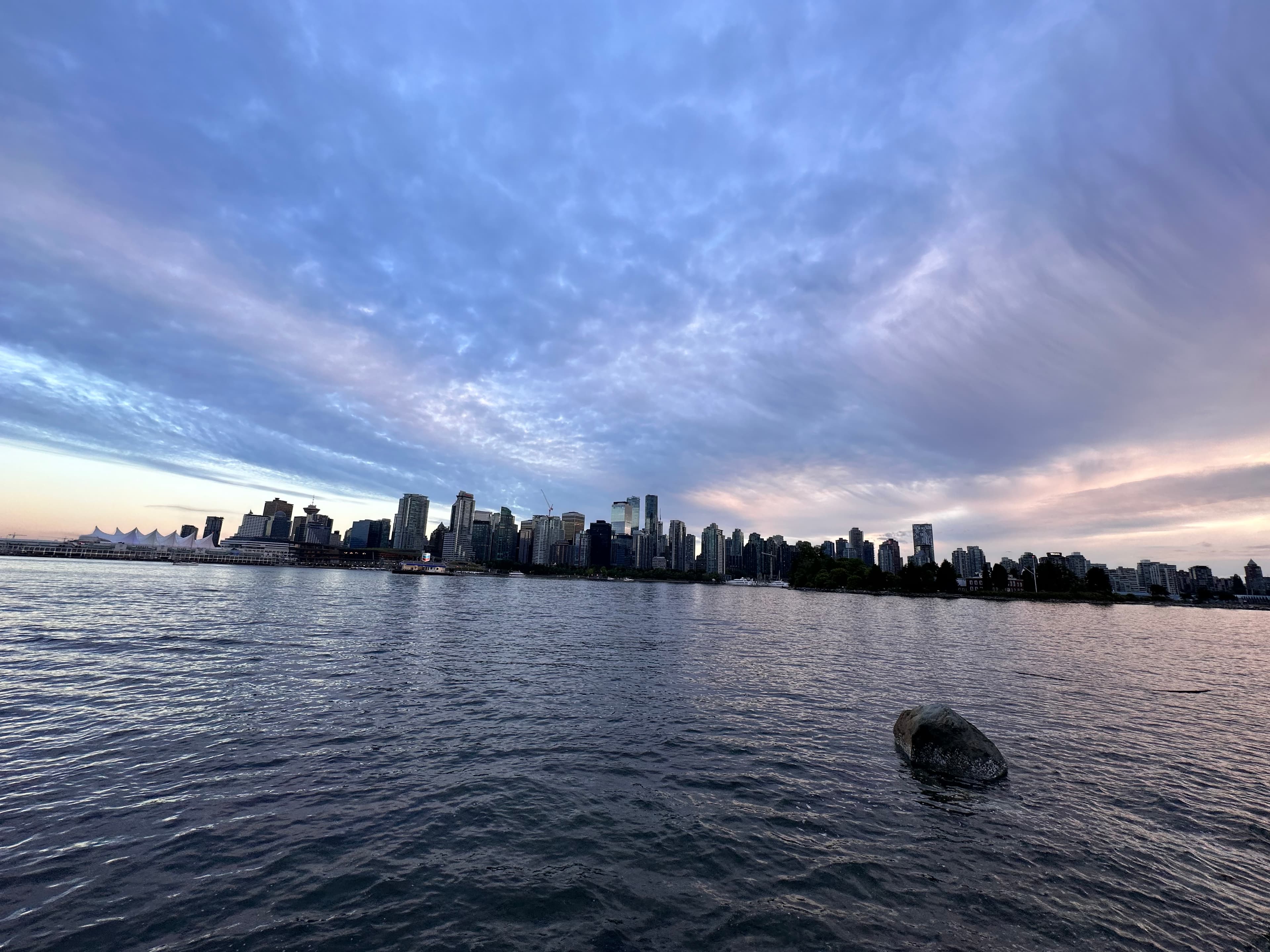 View of a city skyline seen from across a wide river at sunset