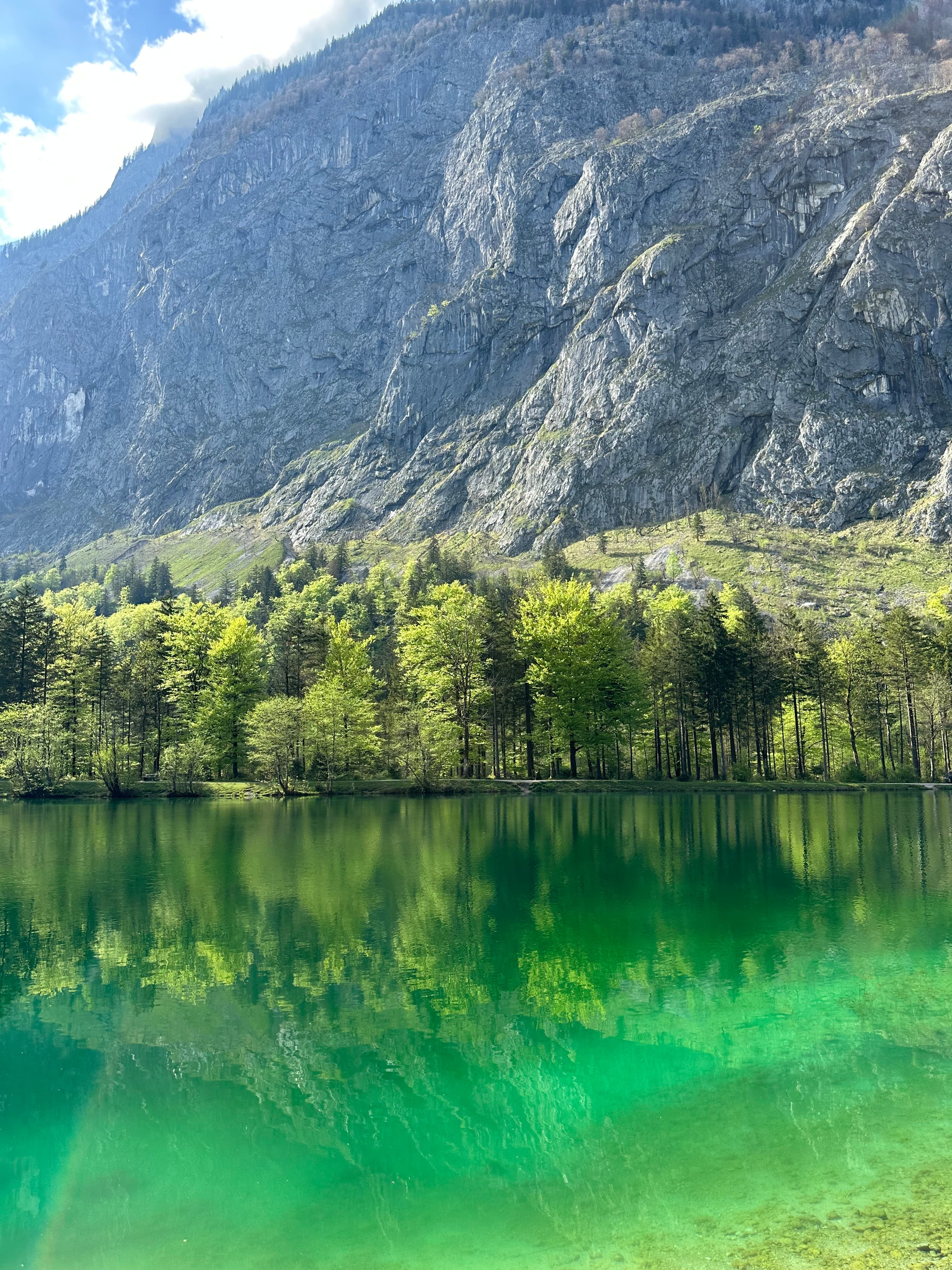 A lake in front of a mountainside during the daytime