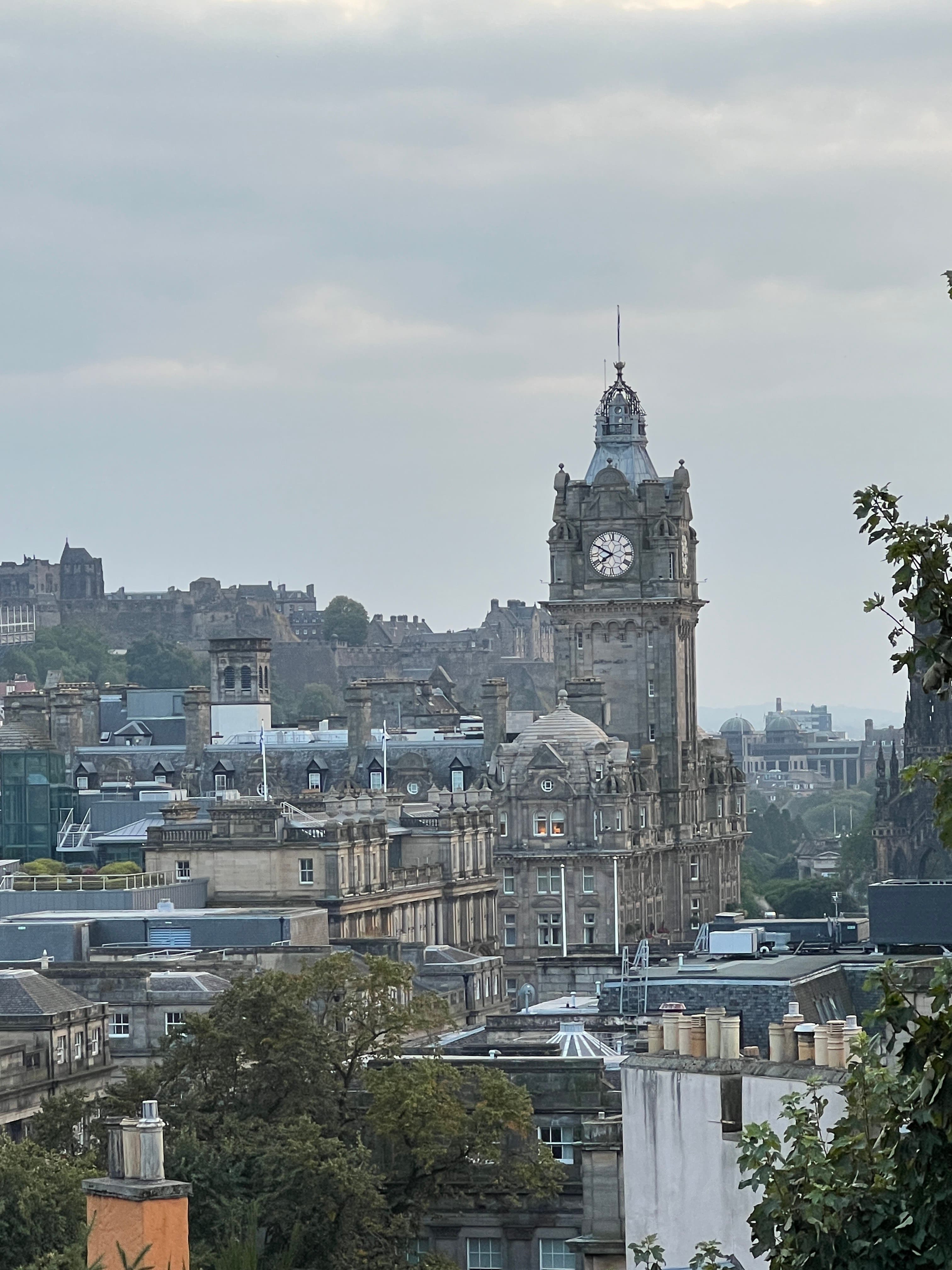 View of a clock tower and surrounding city buildings under cloudy skies