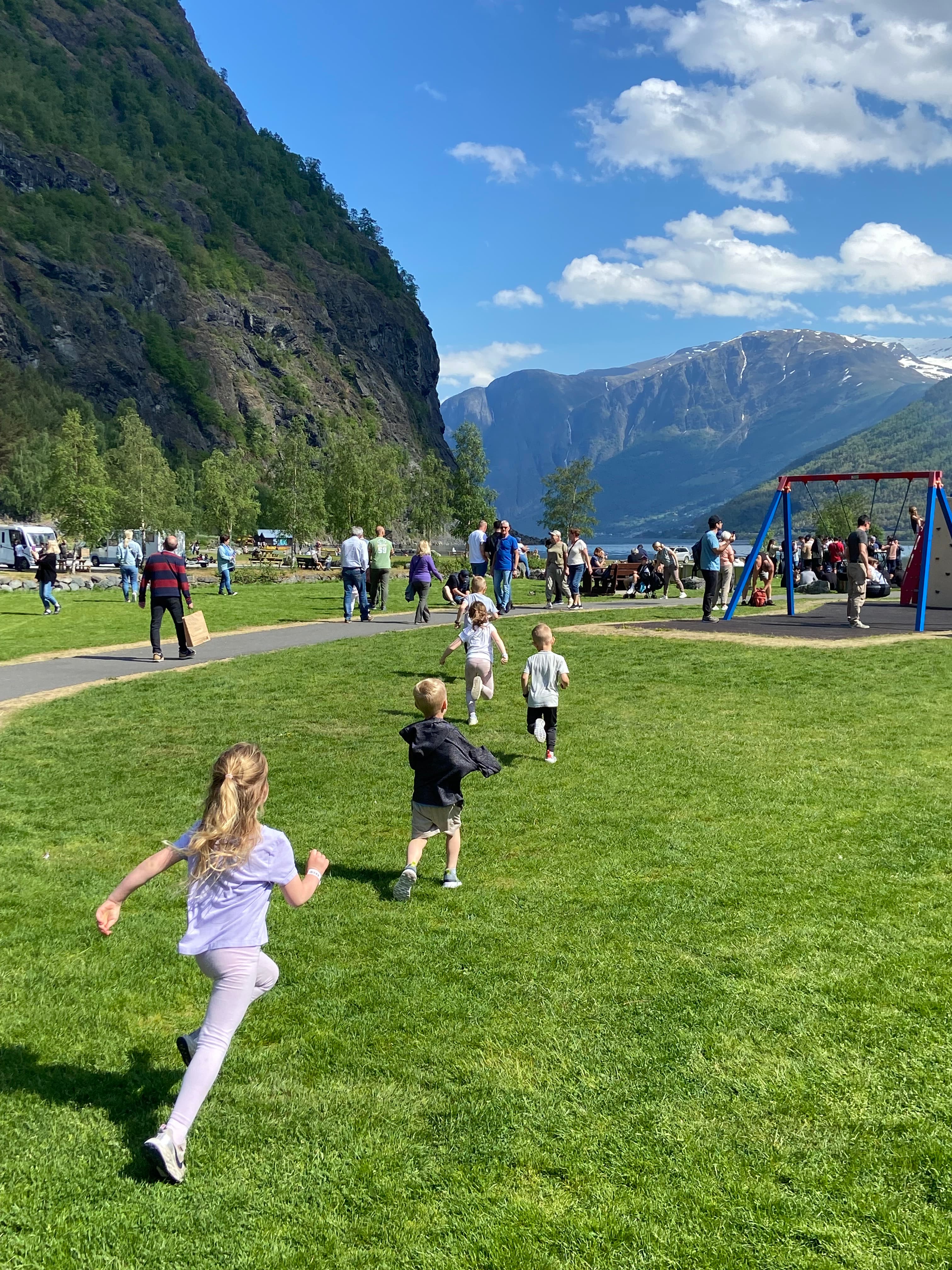 Children running in a grassy field with a beautiful mountain backdrop on a sunny day