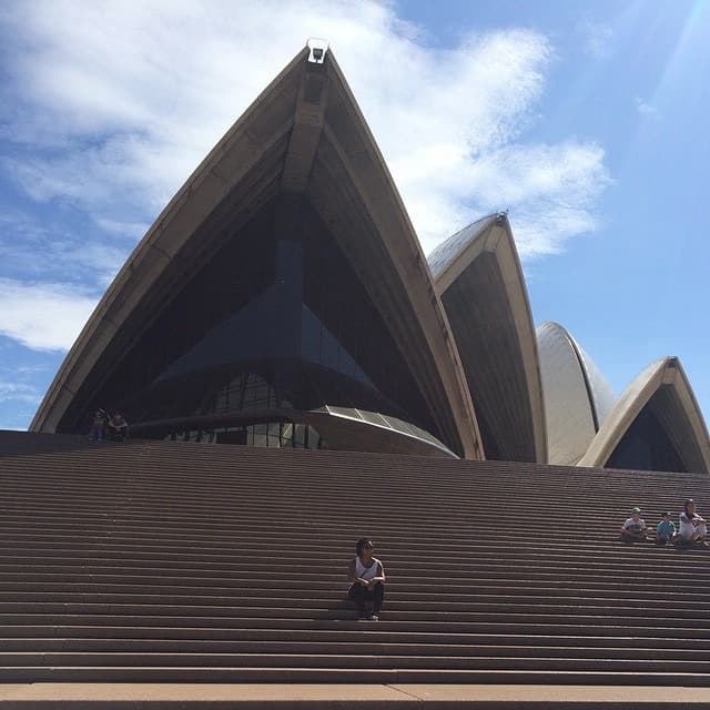 View of advisor sitting on the steps of the Sydney Opera House on a sunny day