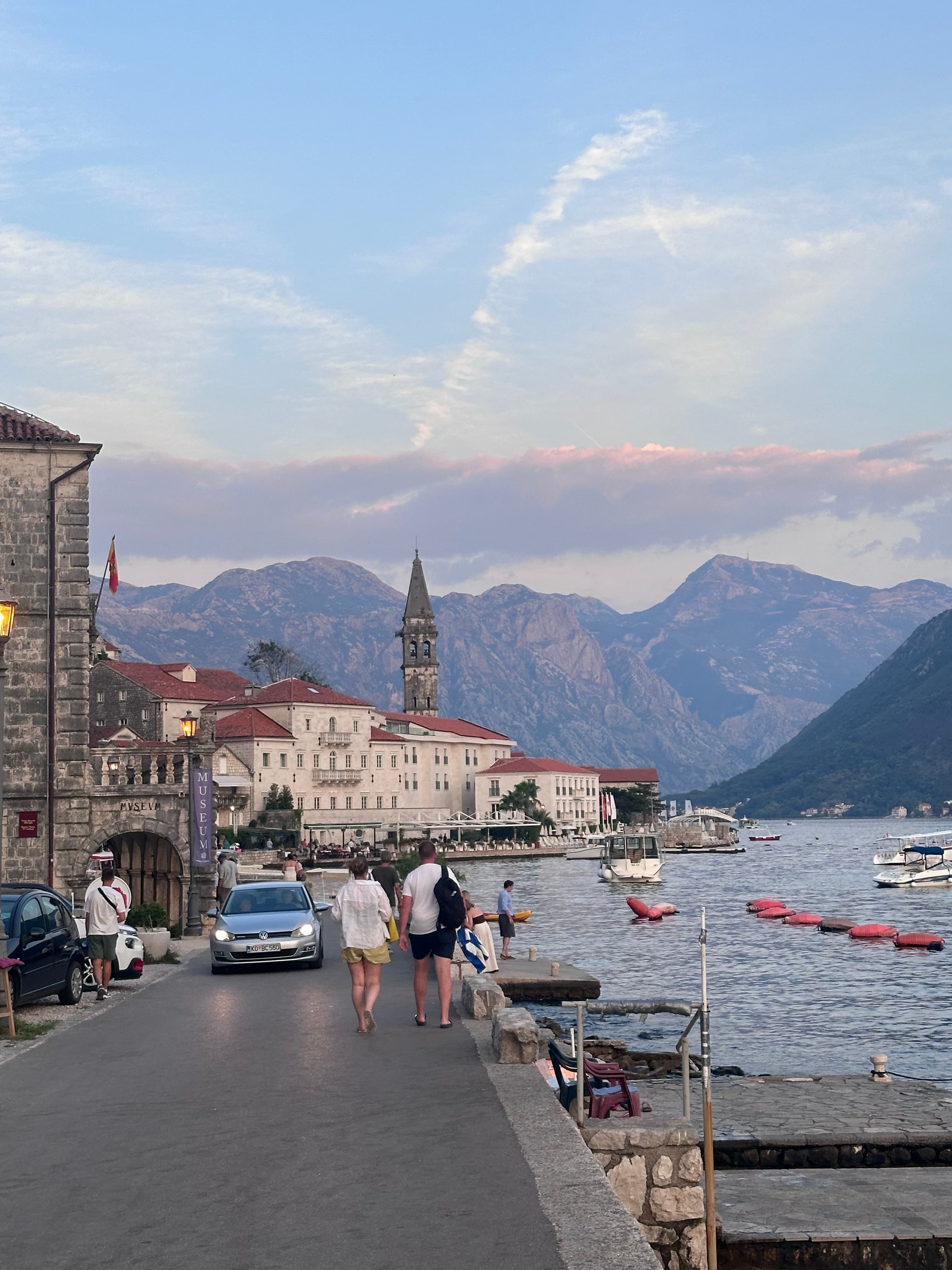Beautiful view of a promenade alongside the sea with pedestrians walking and mountains in the distance