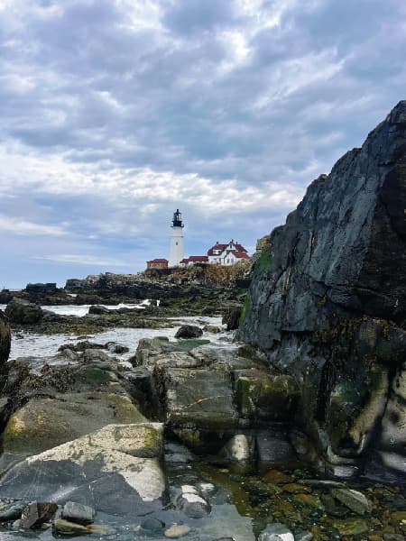 View of a rocky coastline with a white lighthouse in the distance