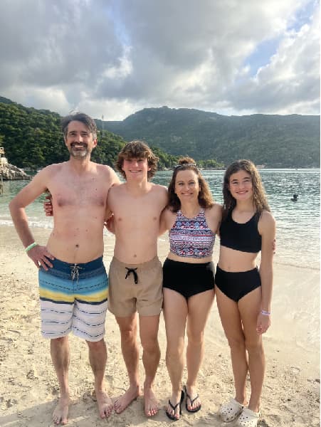 Advisor and family standing side by side on the beach