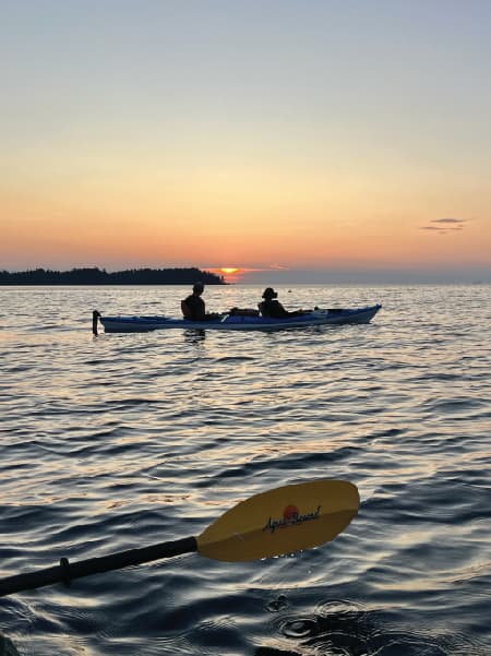 View of two people kayaking at sea during sunset