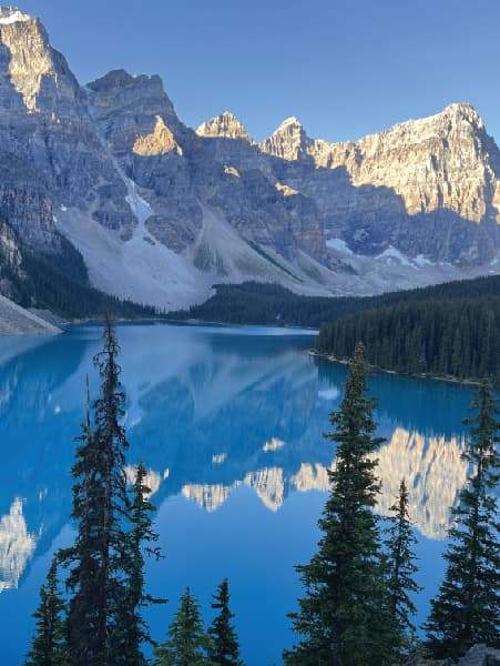 View of a beautiful glacial lake surrounded by snow-capped mountains under clear skies