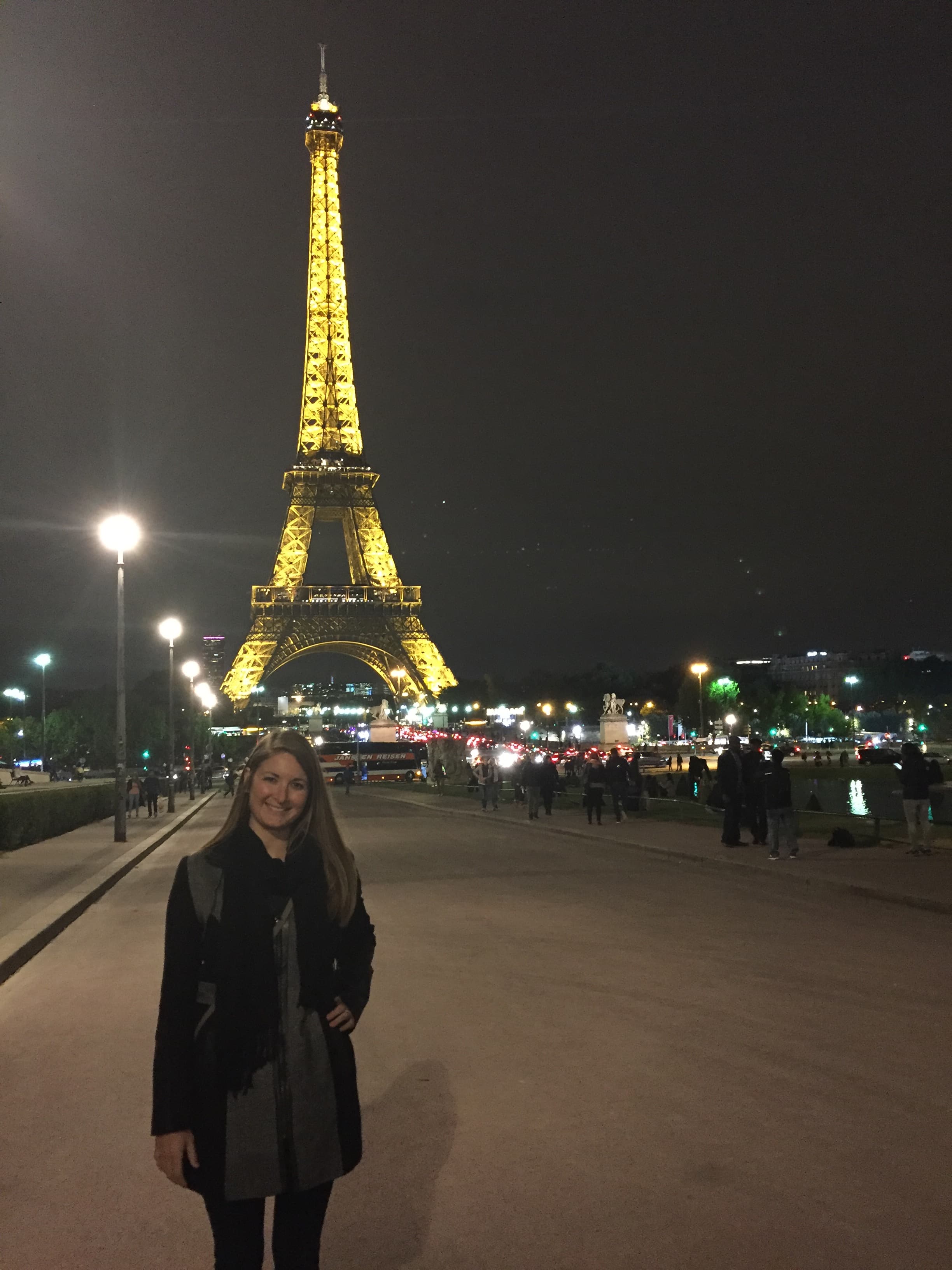 Advisor on the street in night with the Eiffel Tower lit up behind her