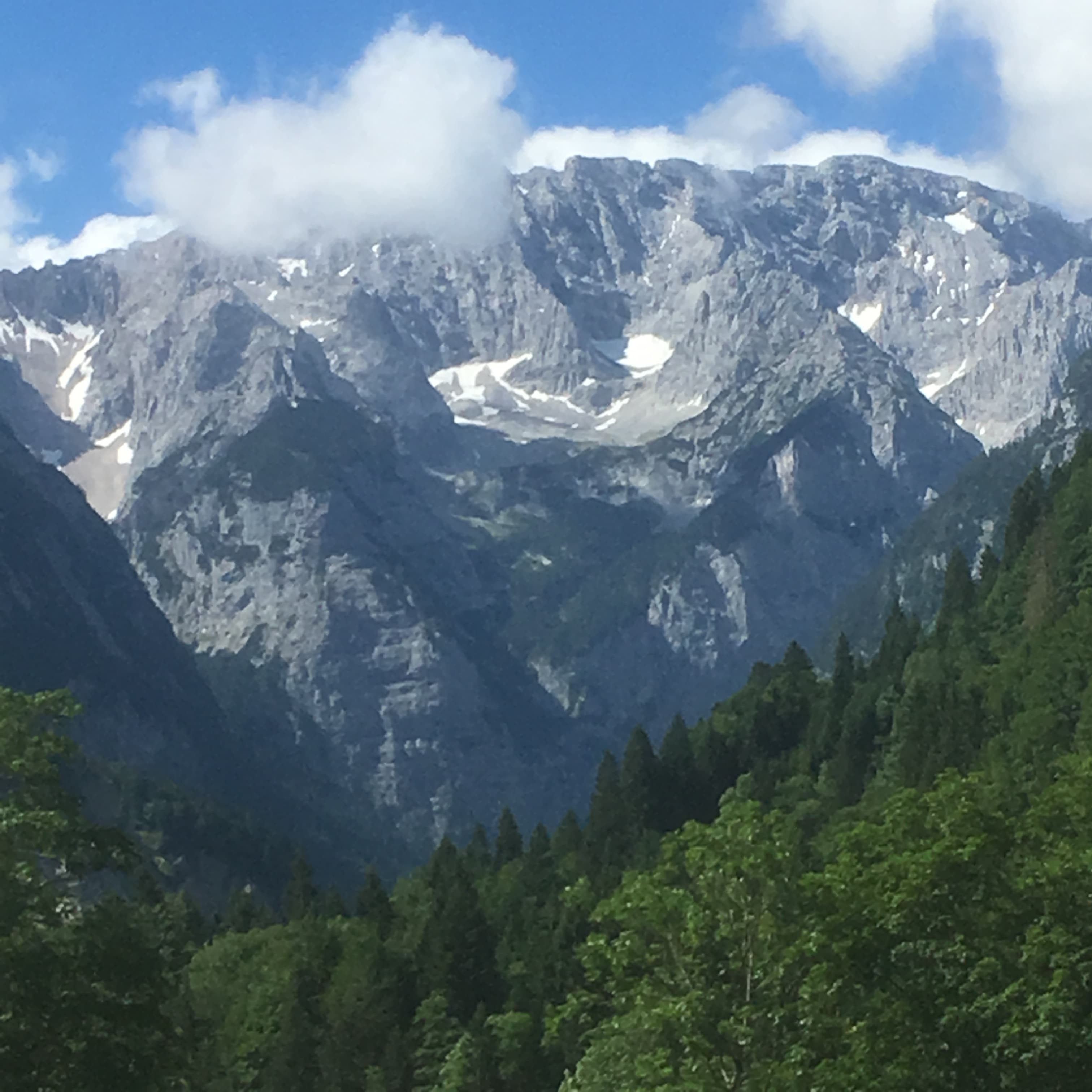 Scenic view of majestic mountains framed by a winding mountain road under a clear blue sky.