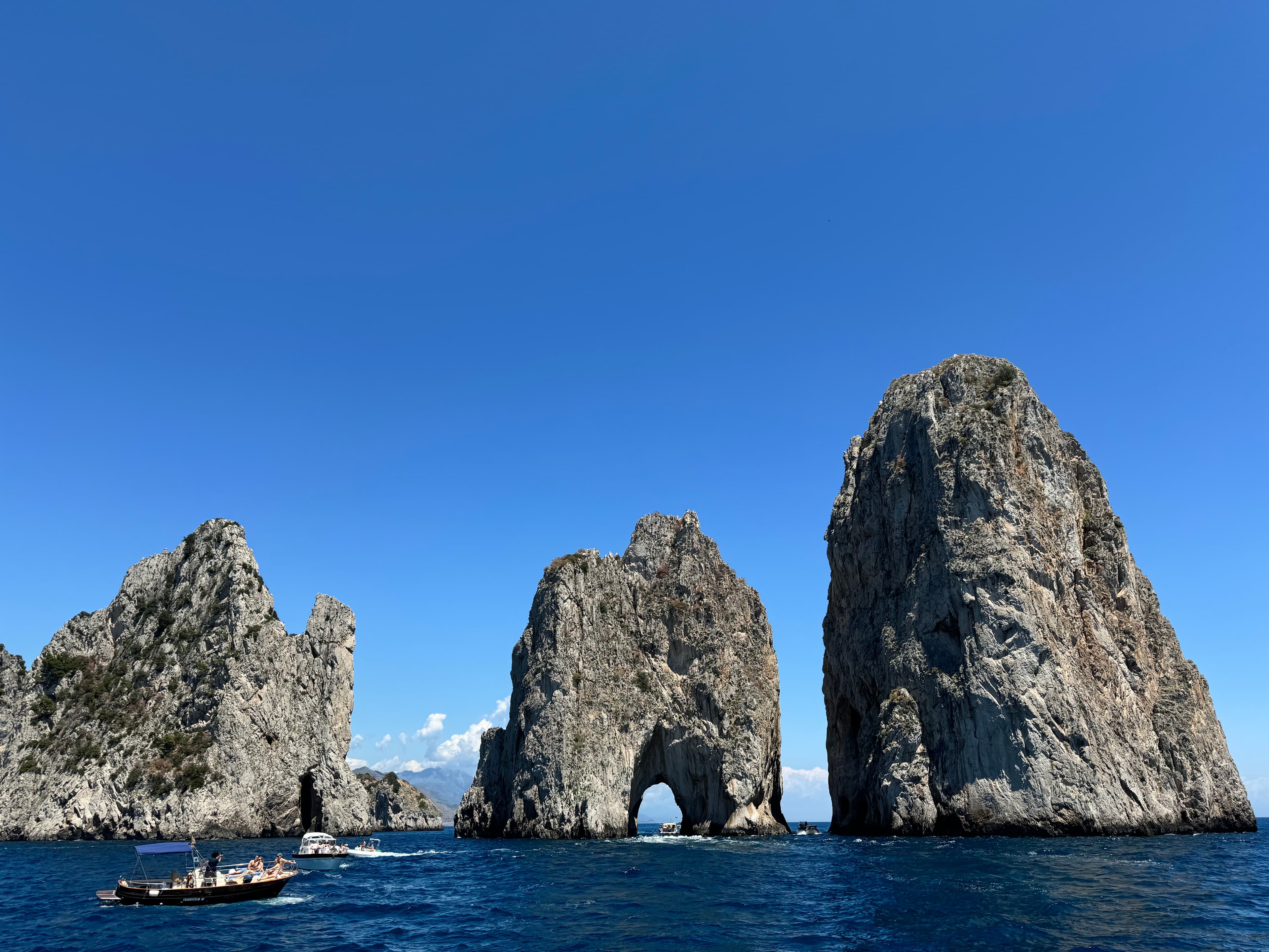 View of three rock formations at sea under clear skies