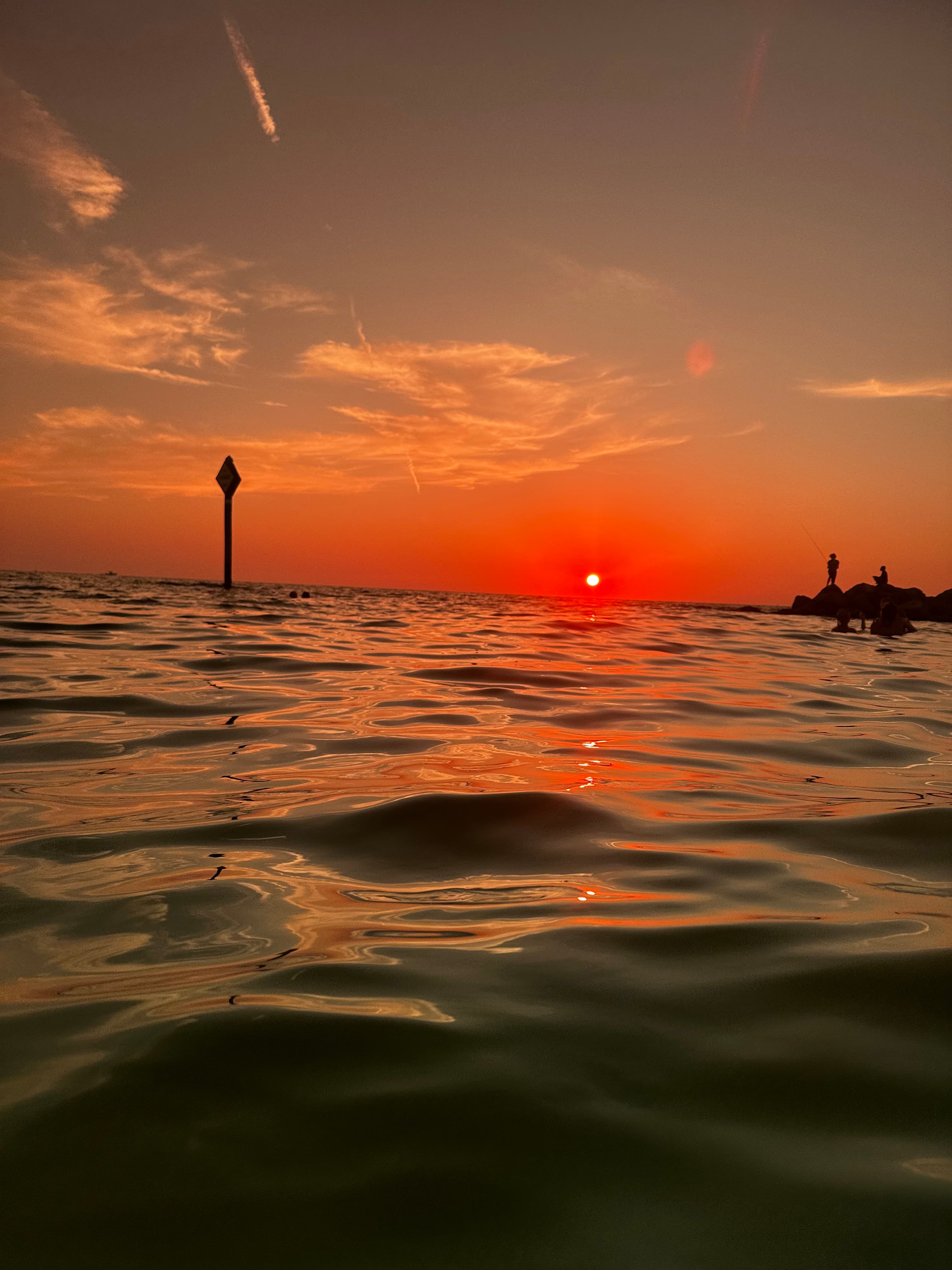 Gentle waves at the beach with an orange sunset in the background.