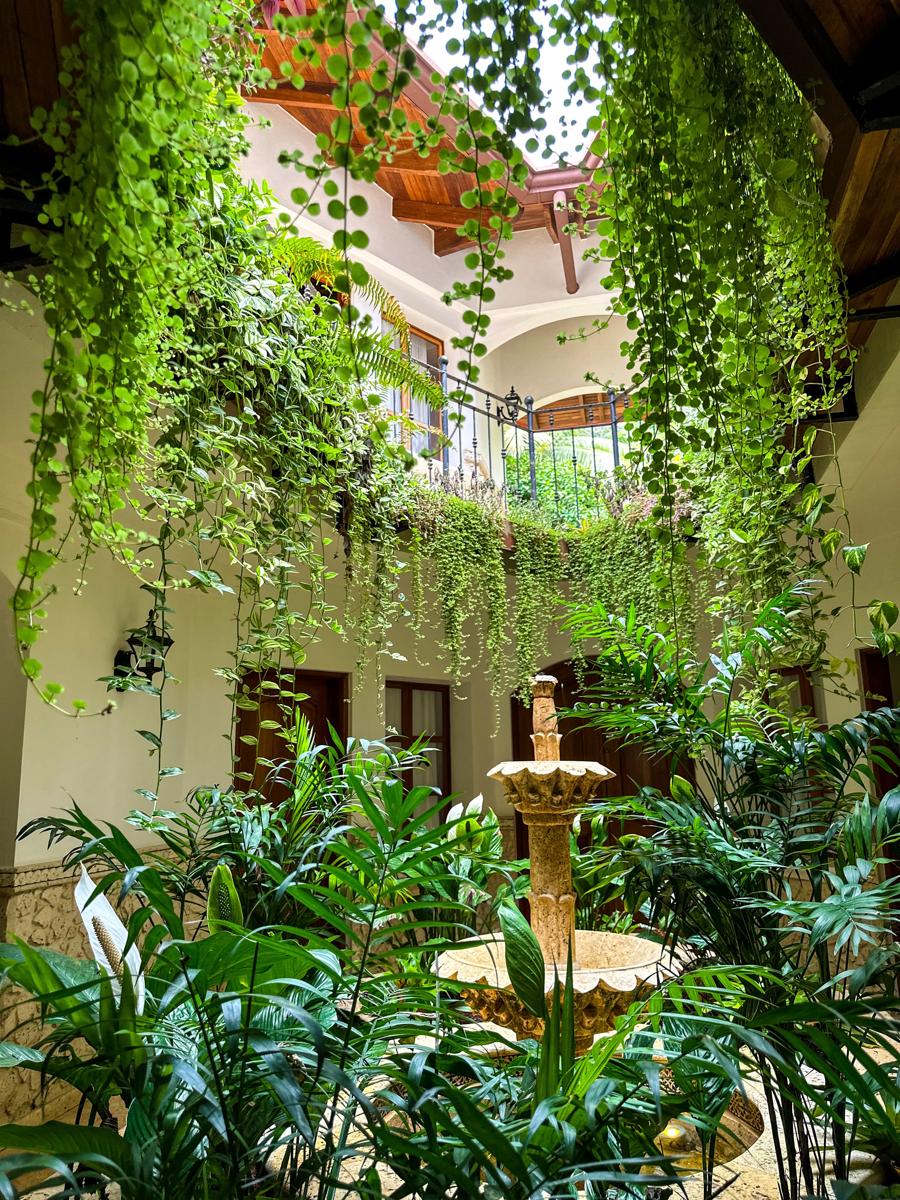 A spacious indoor courtyard featuring lush plants and a central fountain, creating a serene and inviting atmosphere.