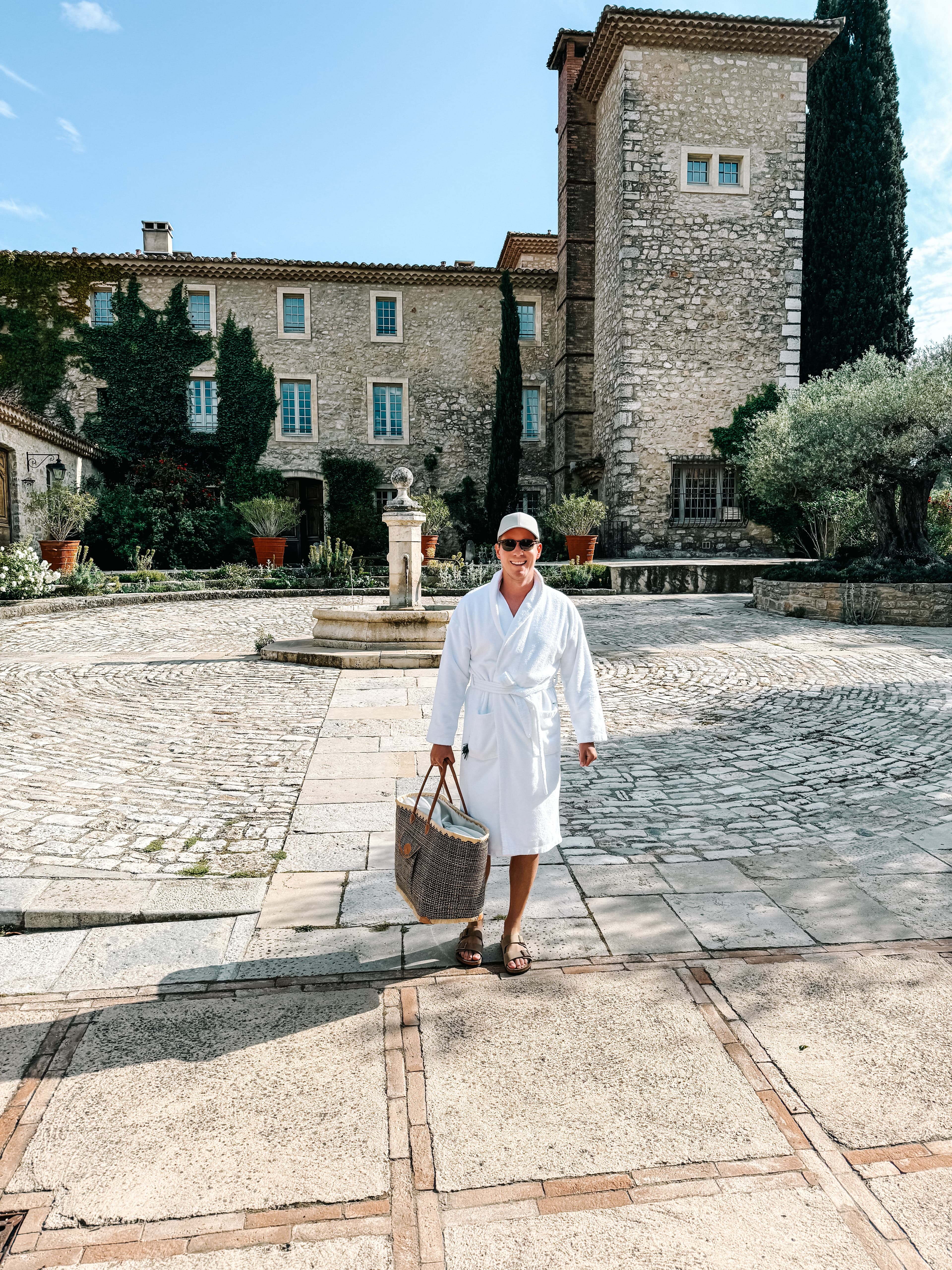 Advisor in a white robe walking in a cobblestone courtyard on a sunny day