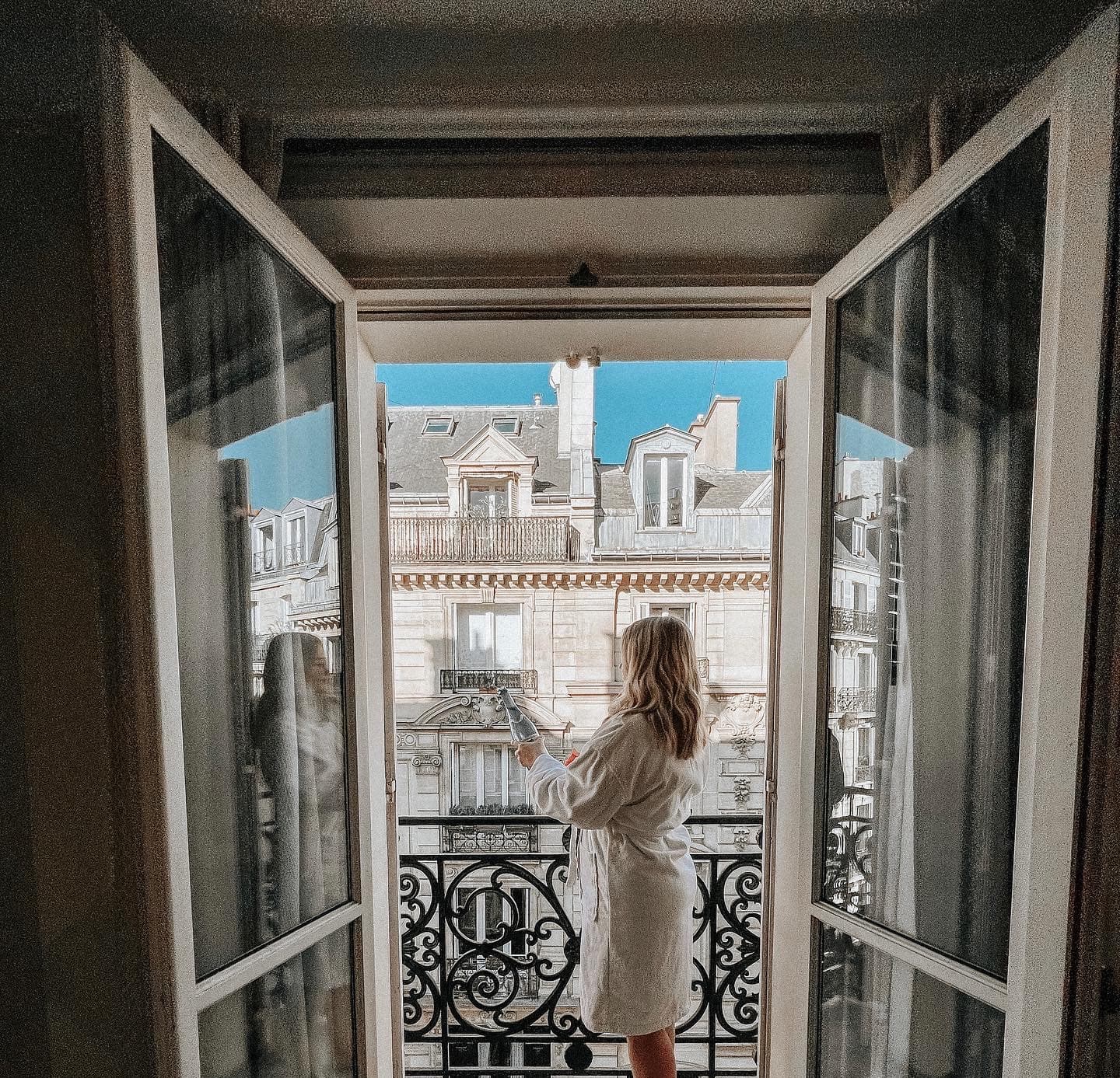 Advisor wearing a bathrobe and popping a bottle on a balcony in Paris