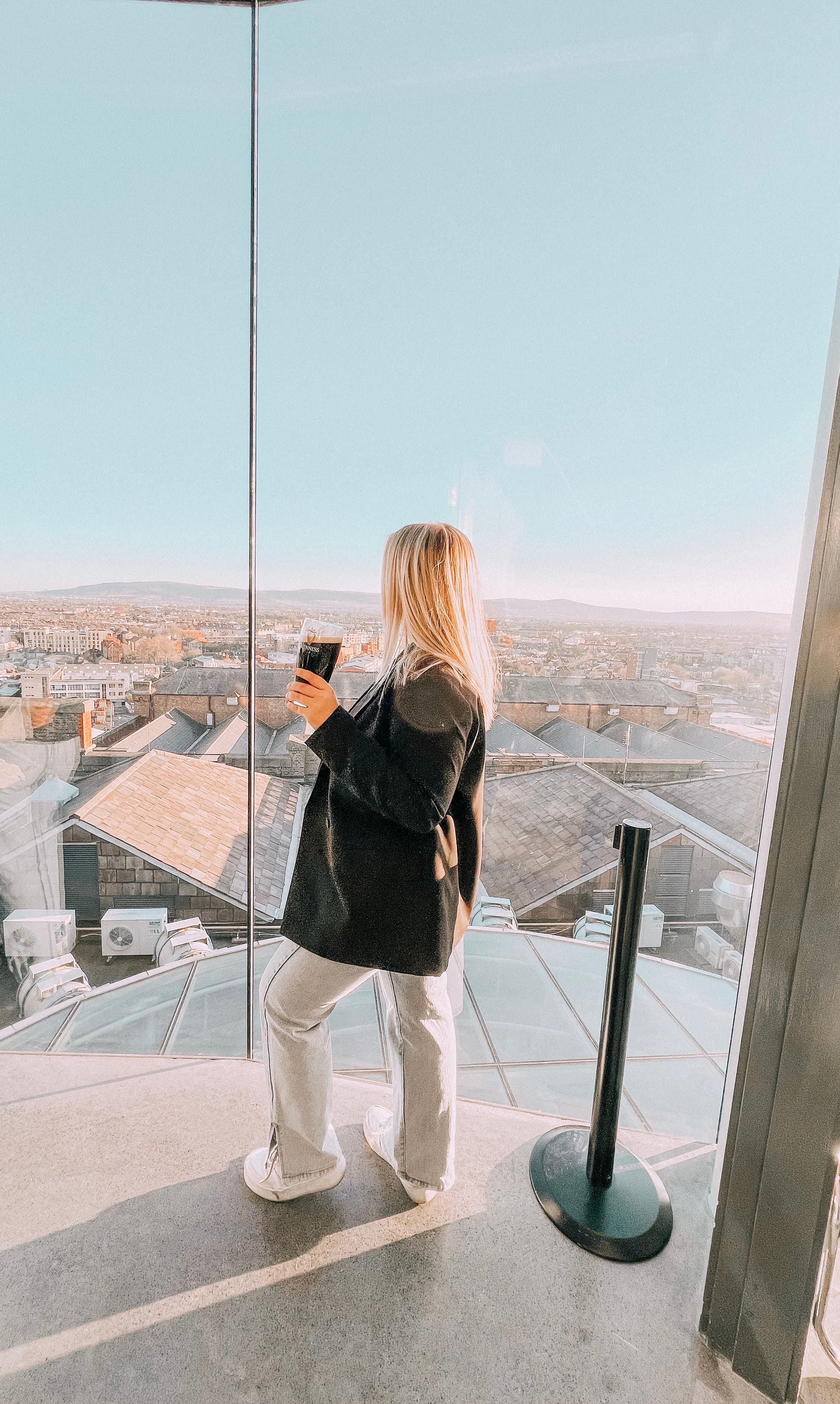 Advisor posing in front of tall glass windows overlooking a cityscape on a clear day