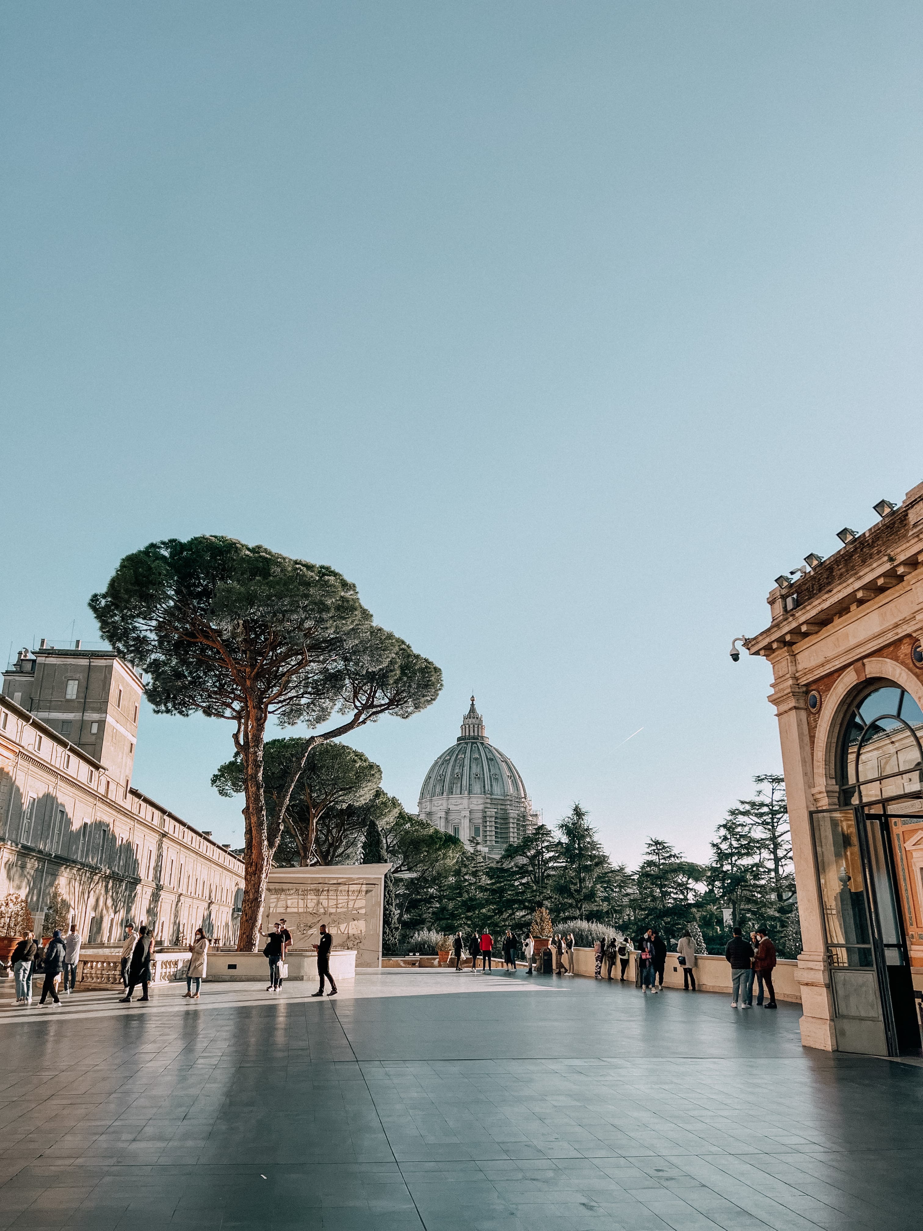 View of an old city plaza with a few pedestrians strolling on a clear day