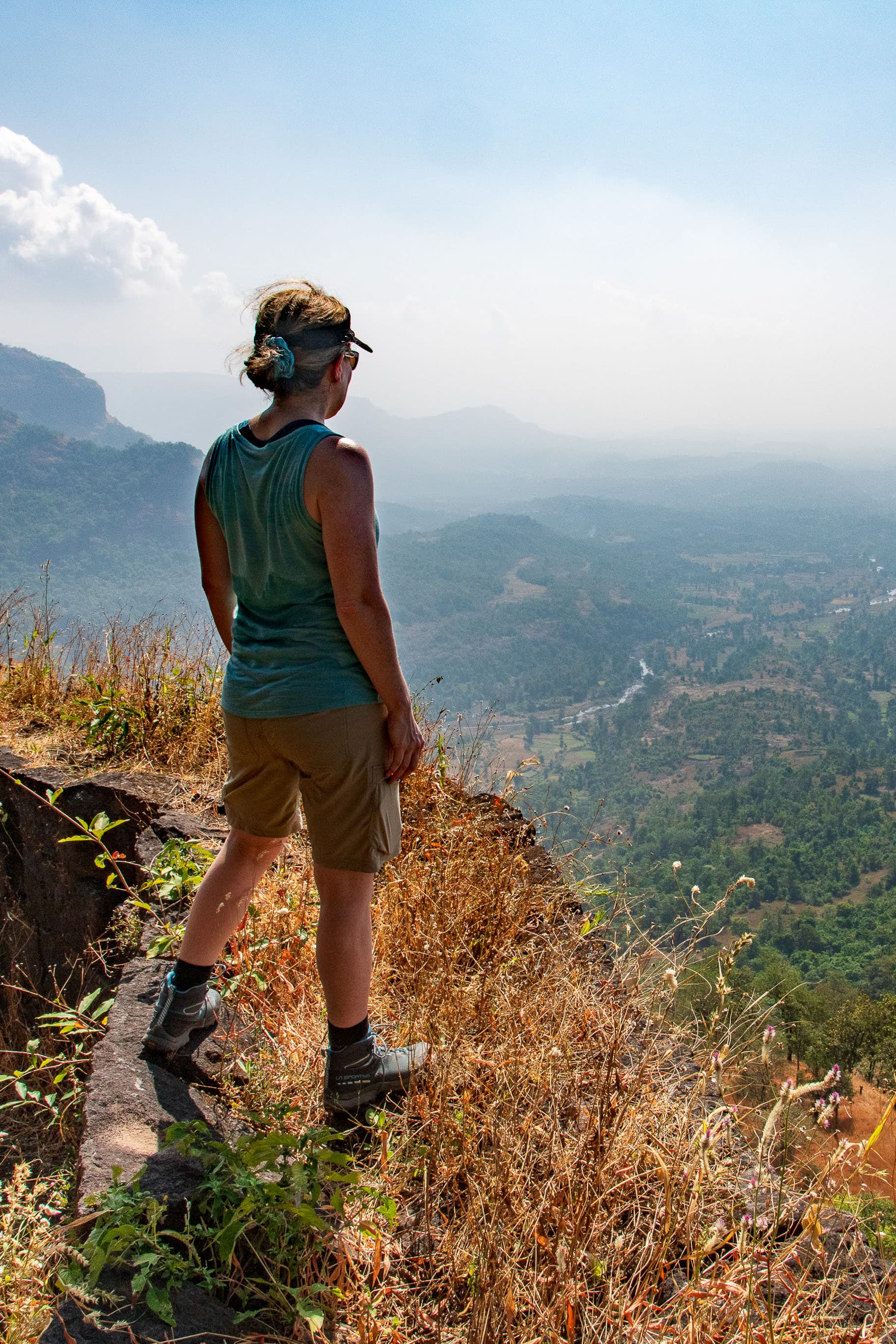 Advisor standing on the edge of a mountain overlook during a hike on a sunny day.