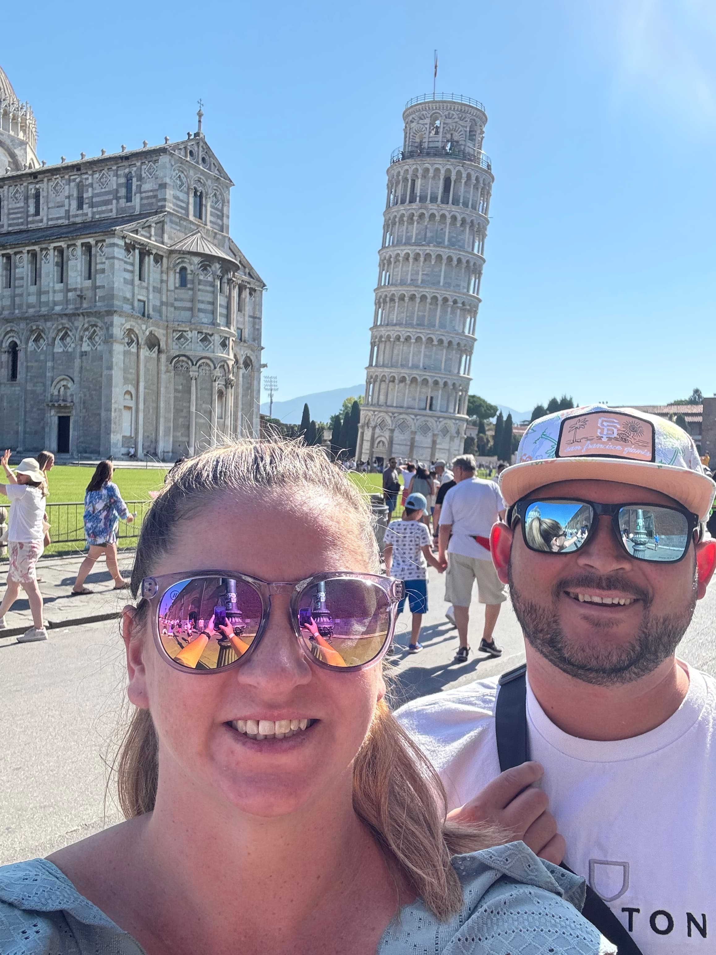 Advisor and partner taking a selfie in front of the leaning tower of Pisa on a sunny day