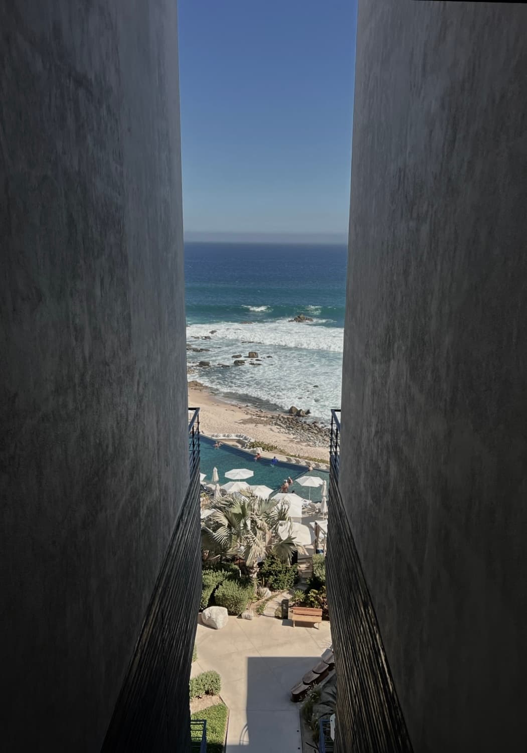 View of the beach seen through a small gap in between buildings on a clear day