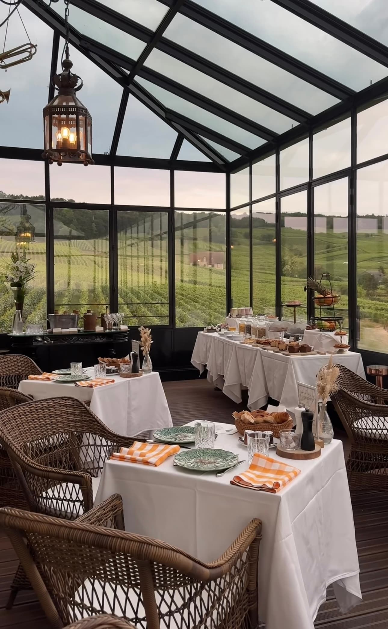 Interior view of empty restaurant tables set inside a glass-walled building in the country