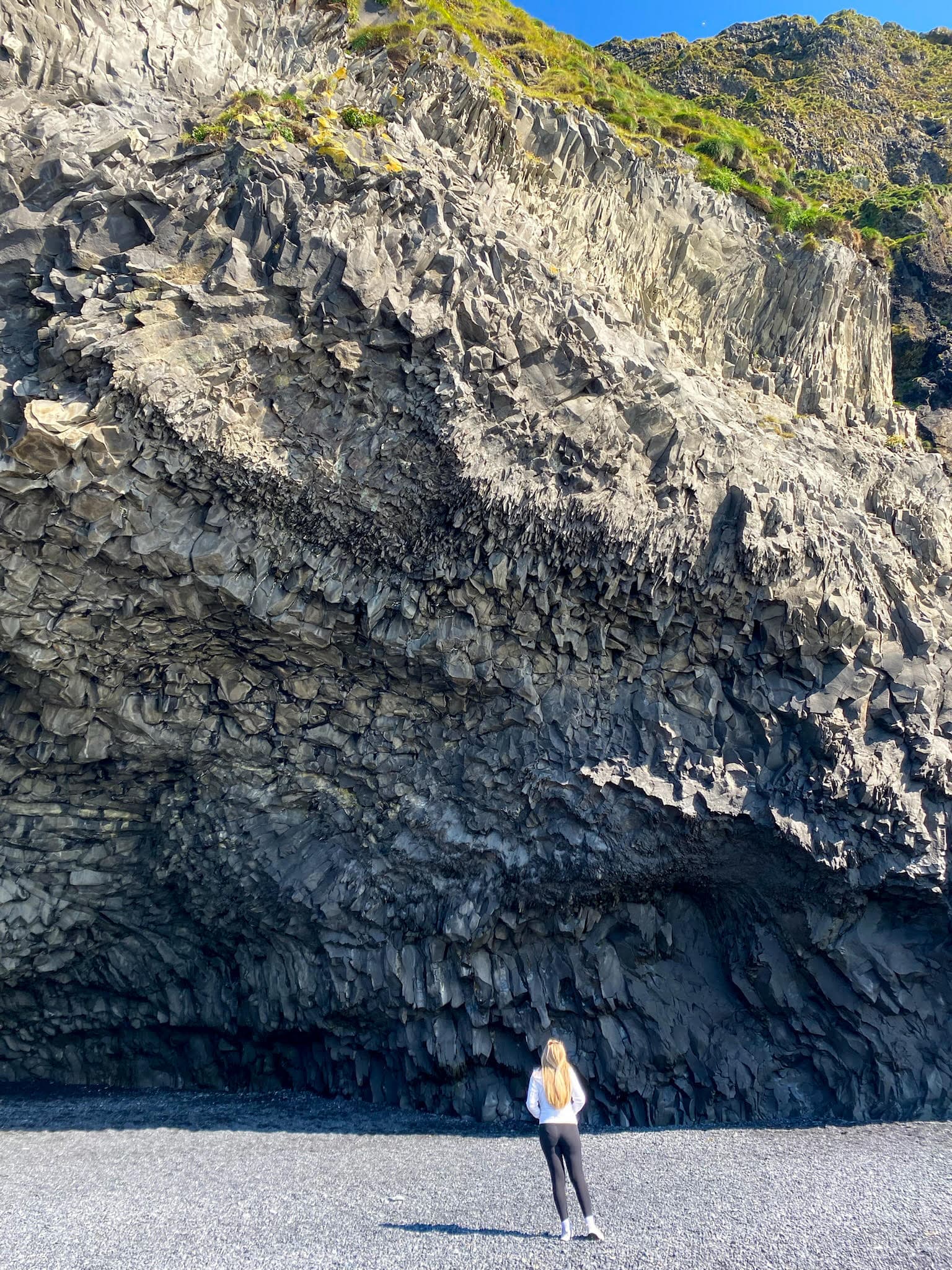 Advisor posing on a pebble beach with a cliff face behind her