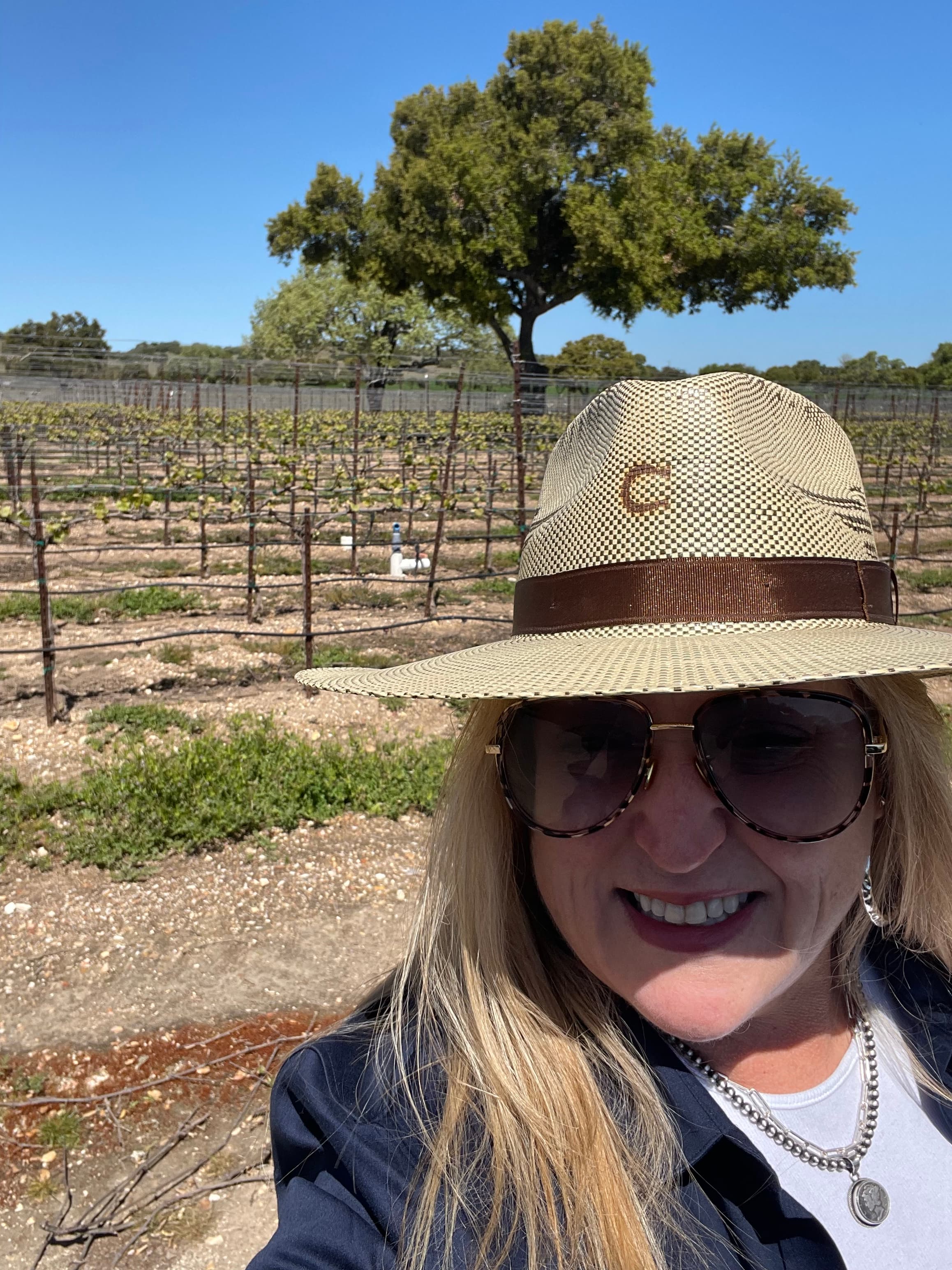 Advisor wearing a hat and taking a selfie at a vineyard on a clear day