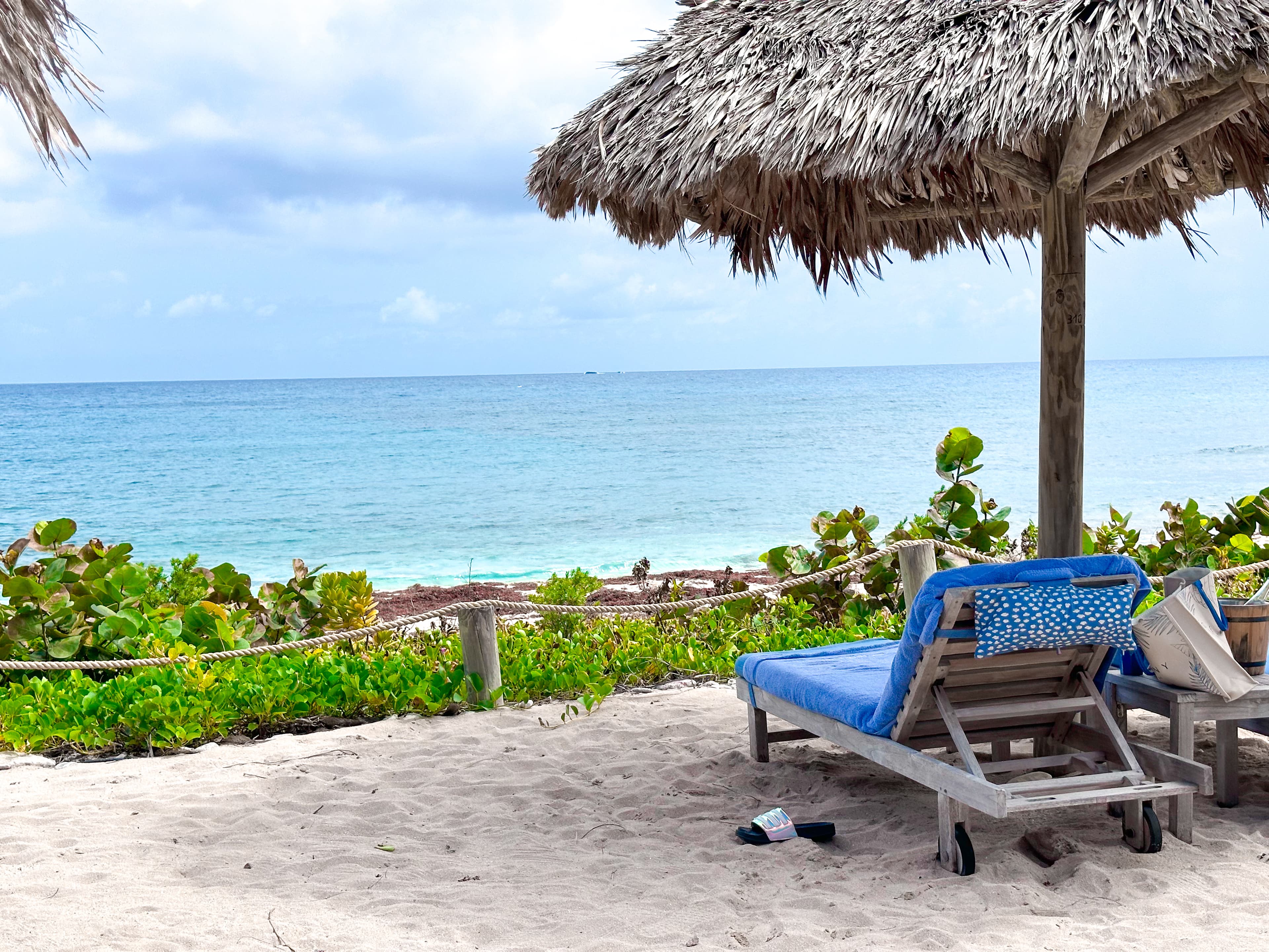 View of lounge chair with towel under an umbrella overlooking the sea on a cloudy day
