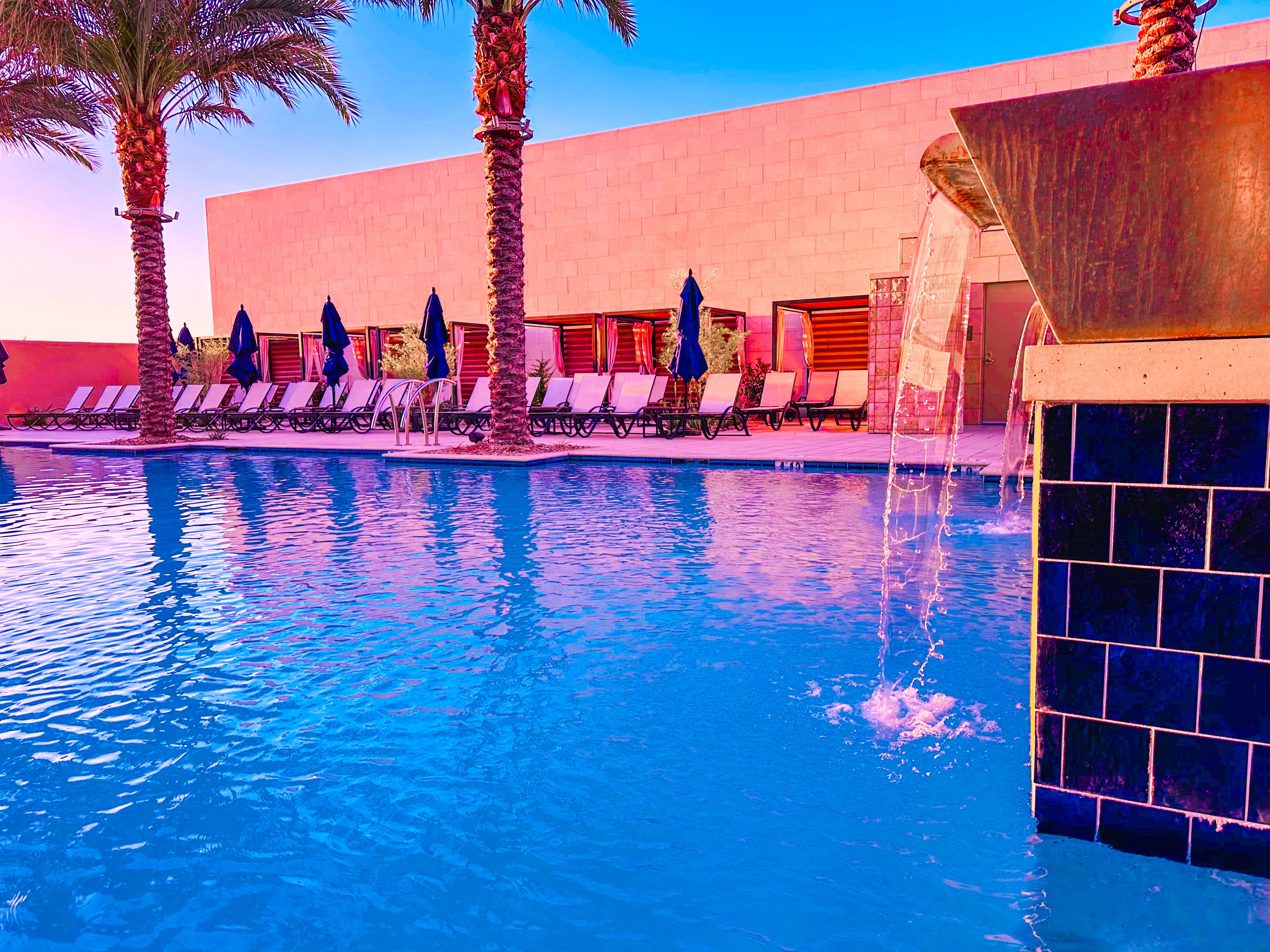 Technicolor photo of a large hotel swimming pool with empty lounge chairs to one side