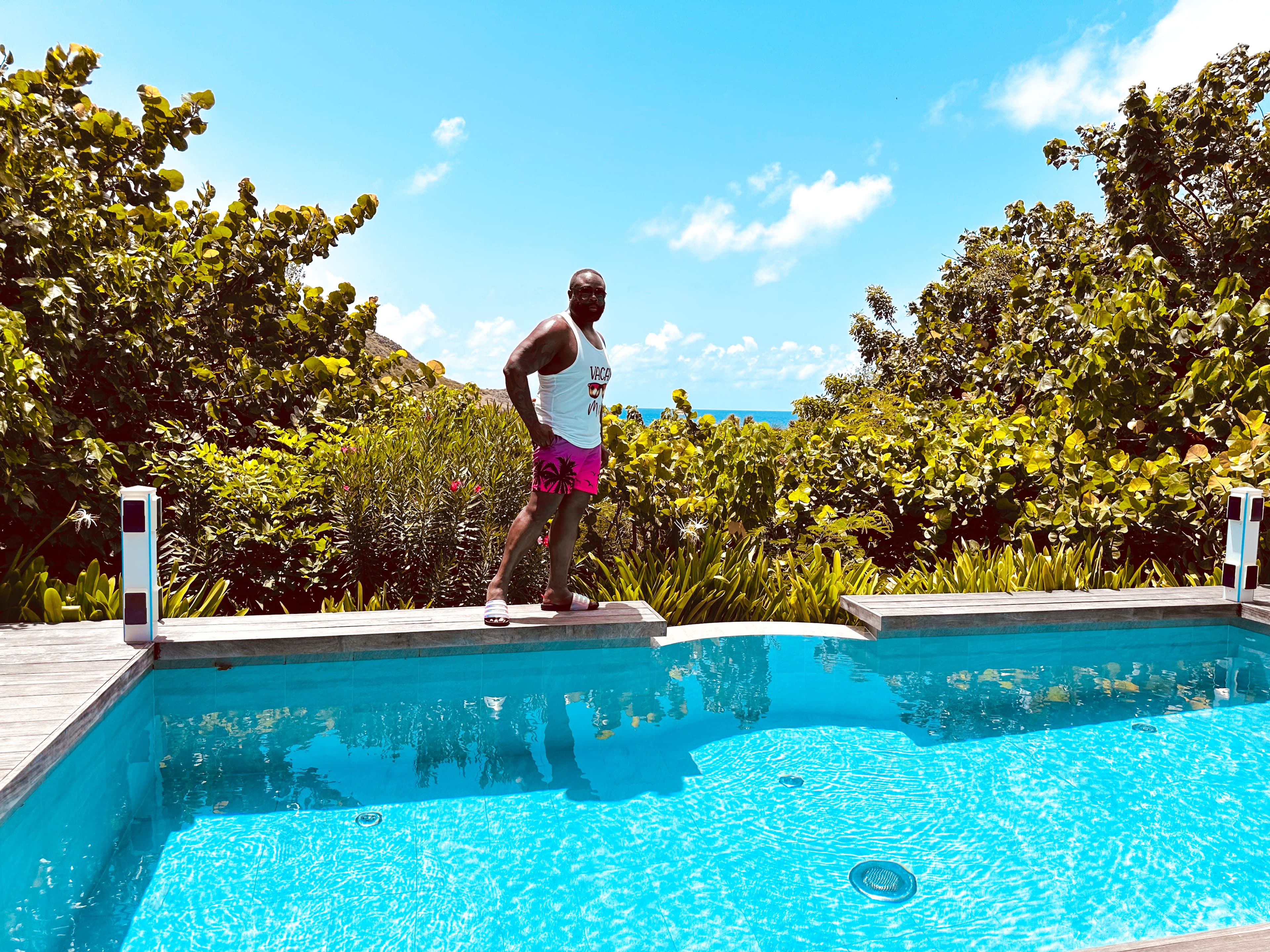 Advisor walking along the edge of a swimming pool surrounded by trees