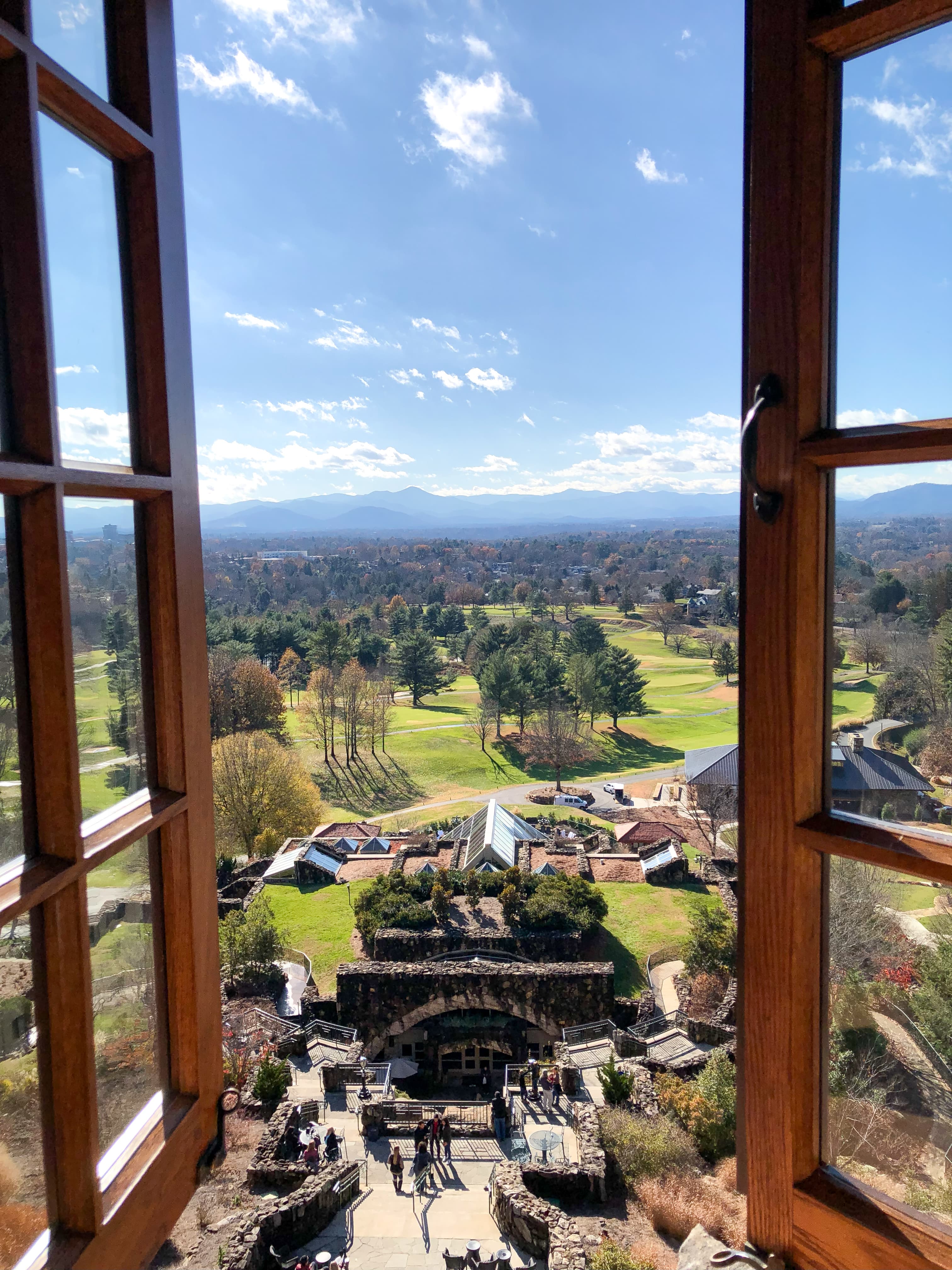 View of a green countryside seen through an open wooden window