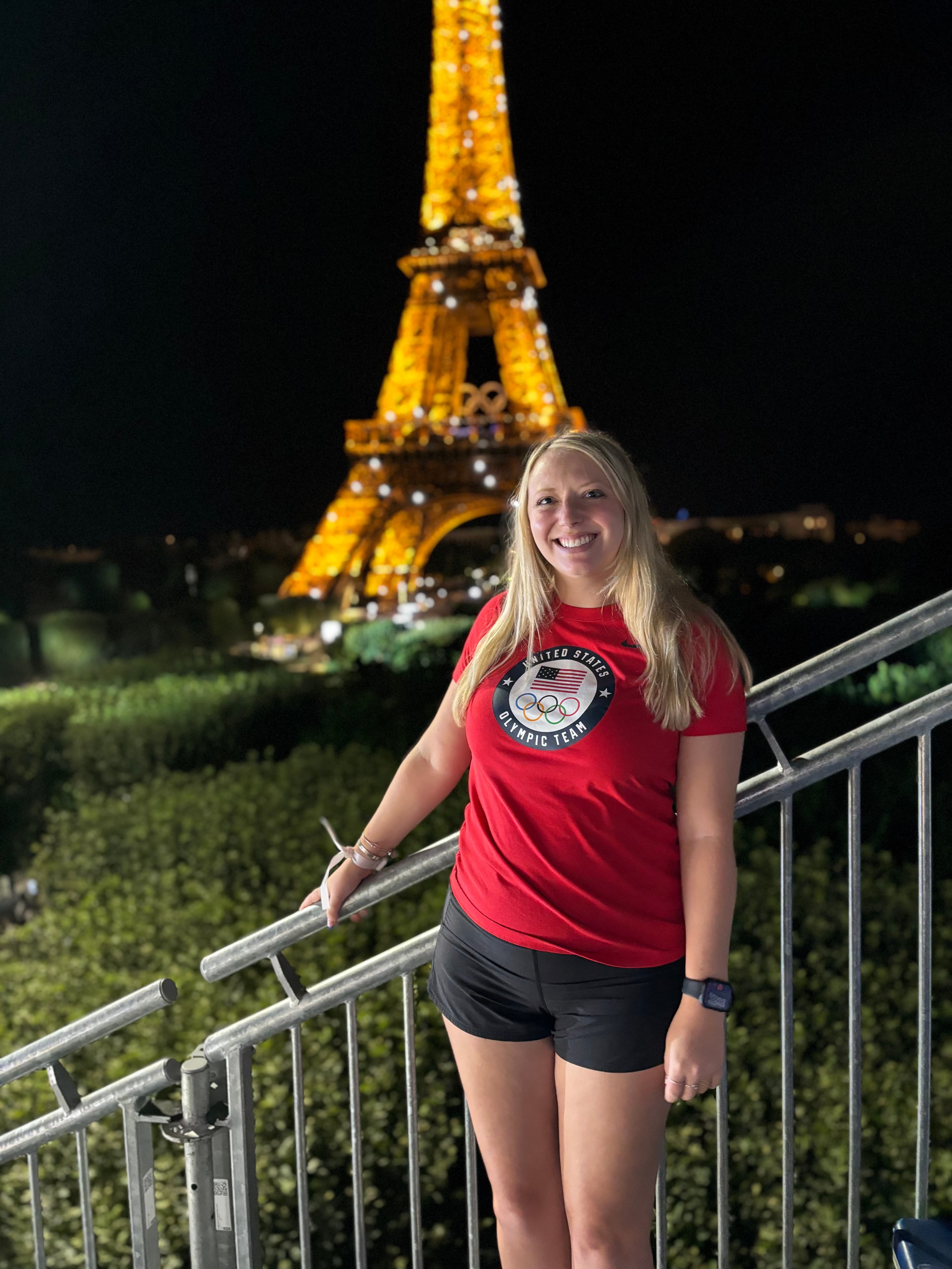 Advisor in a red t-shirt with the Eiffel Tower lit up behind her at night