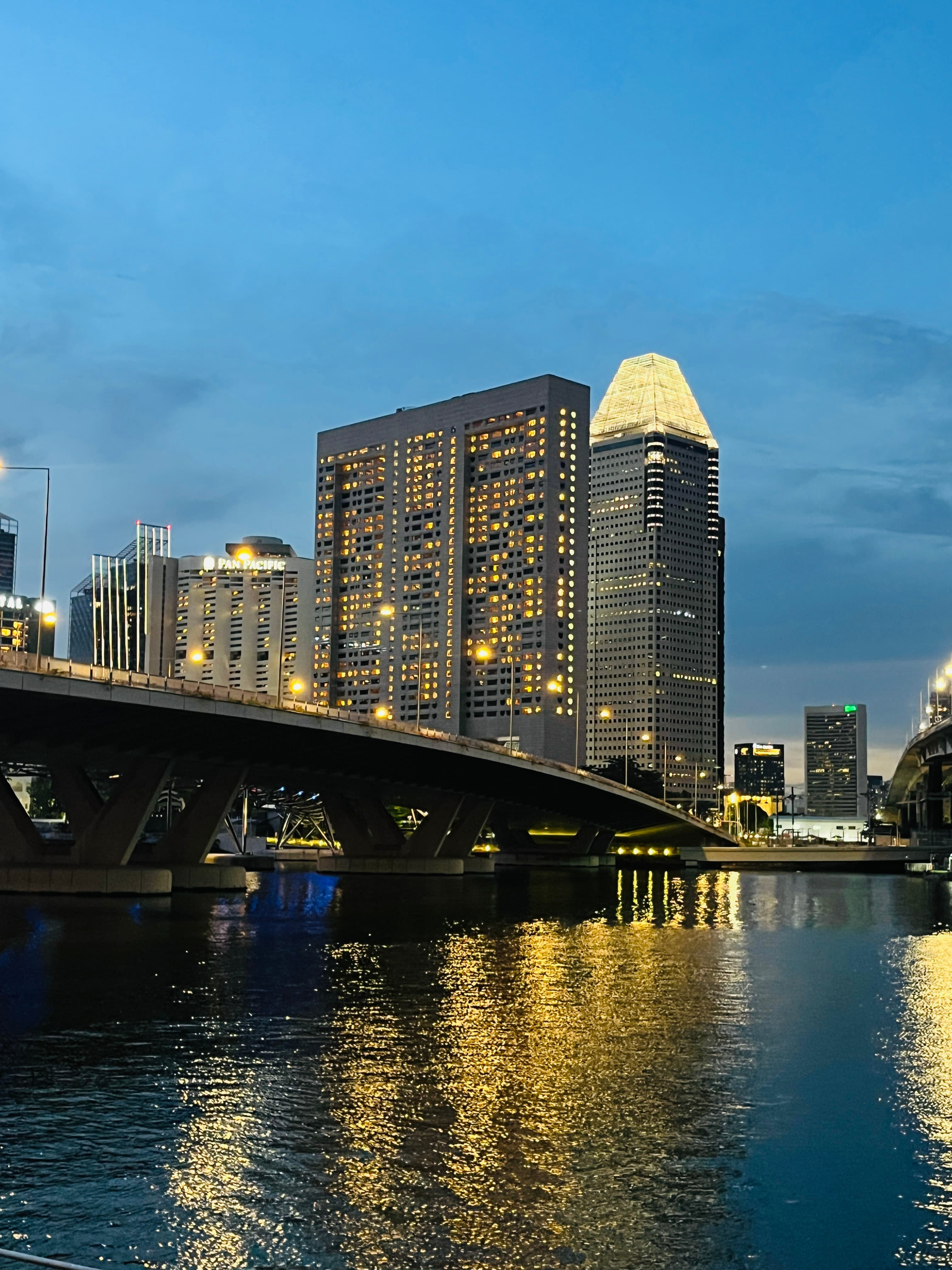 View of city buildings with lights by a river at dusk