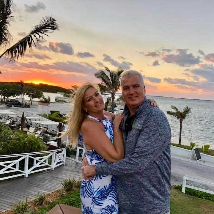 Advisor and partner hugging outdoors with the sea and sunset in the background