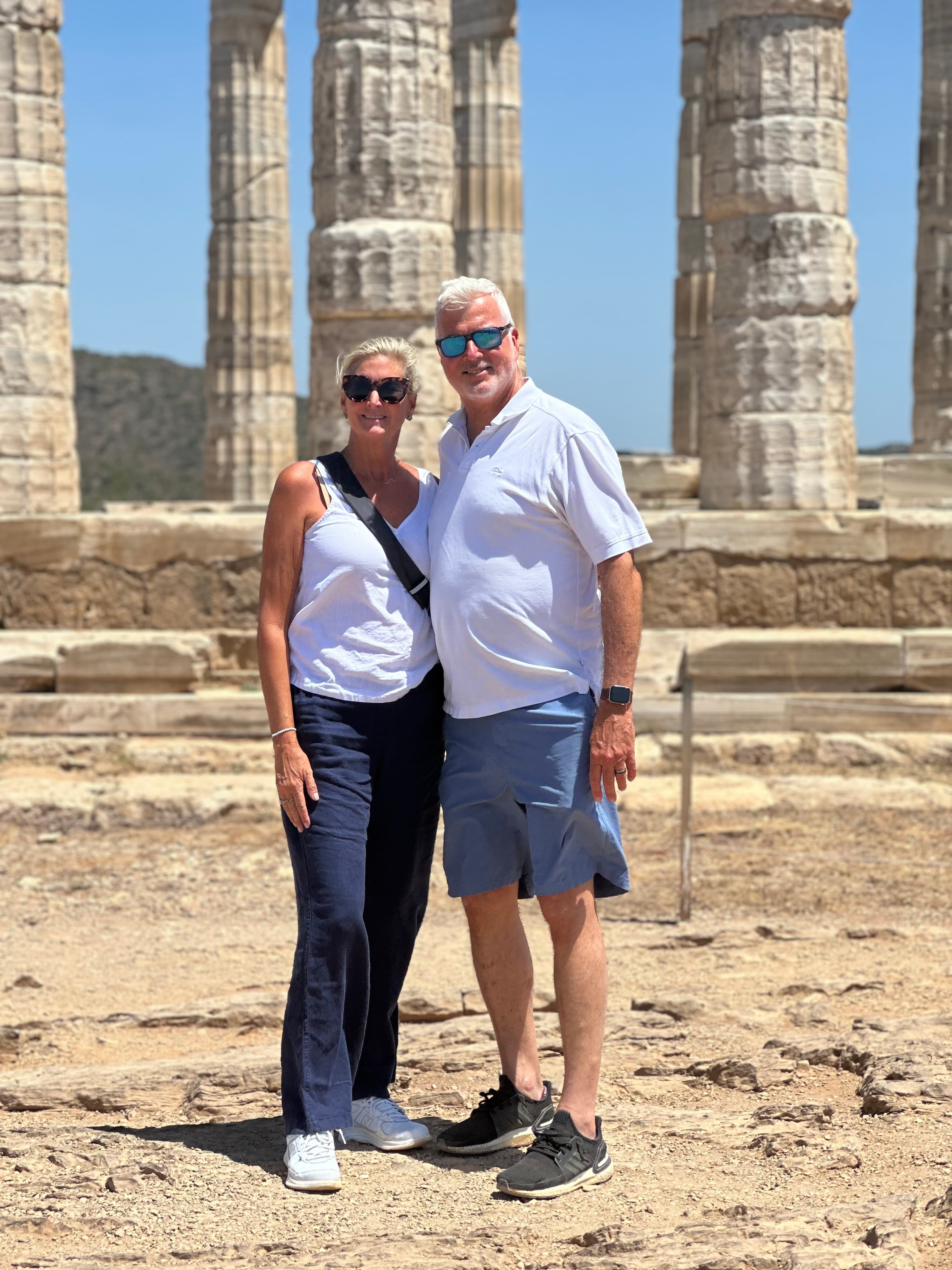 Advisor and partner posing side by side in front of ancient columns on a sunny day