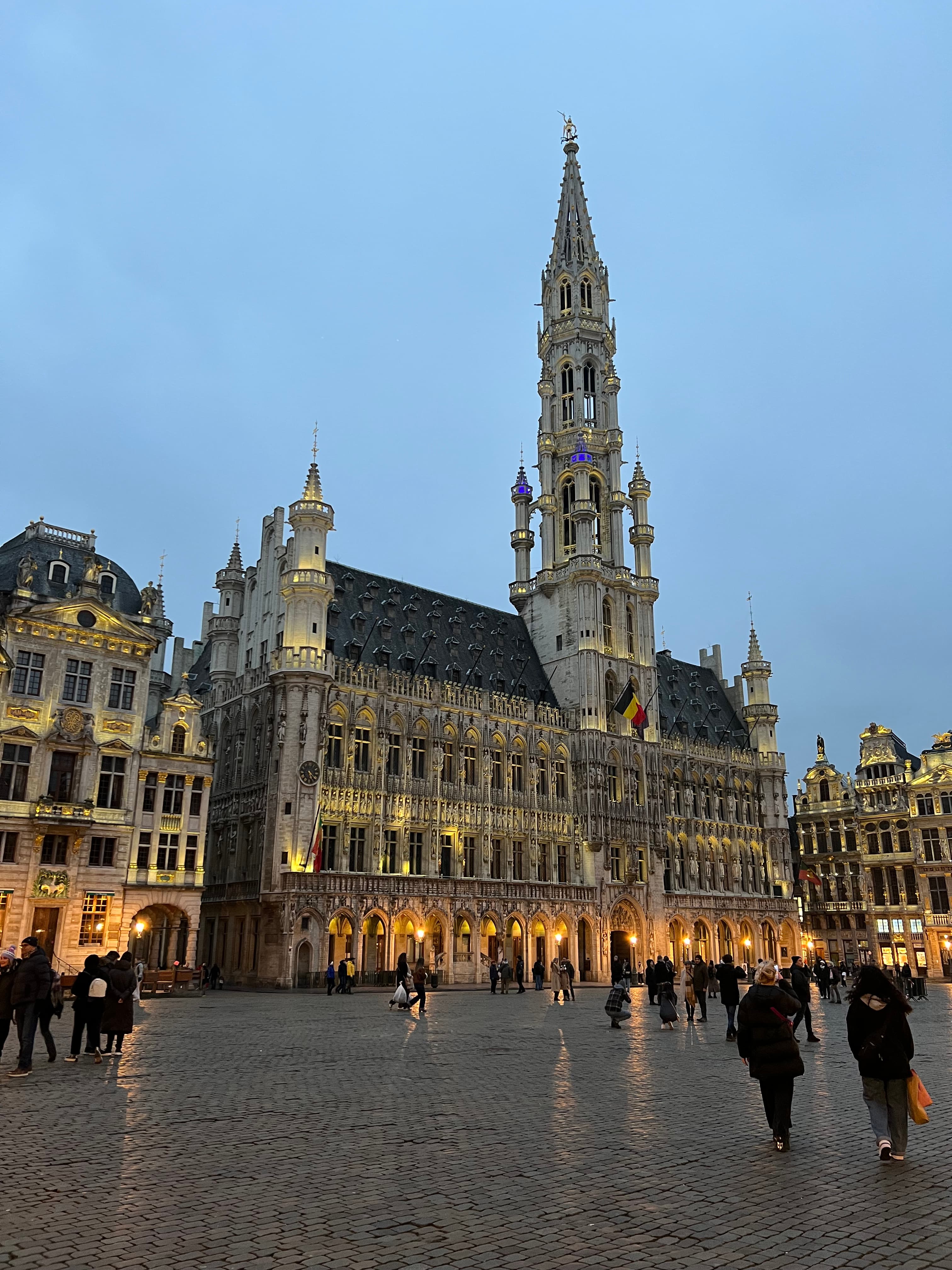 View of an old building in a city plaza at dusk under cloudy skies