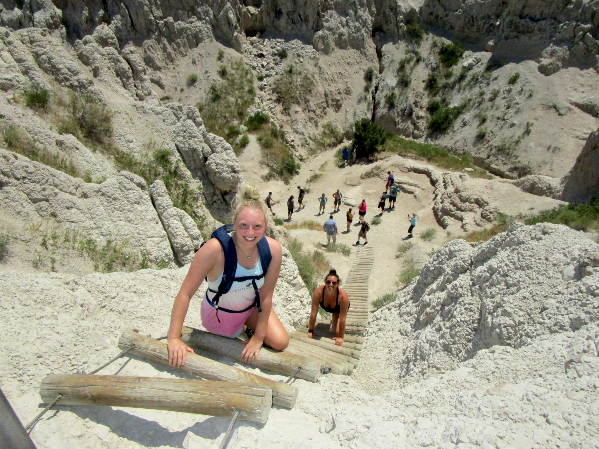 Advisor climbing up a steep wooden ladder through the mountains with people on the ground below