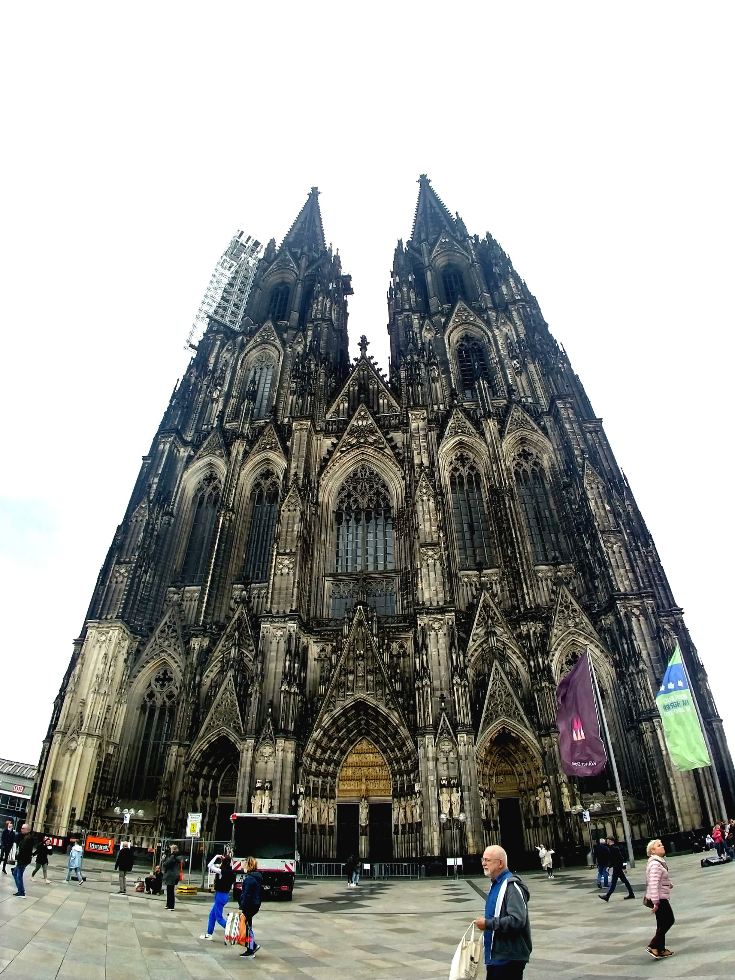 View of an old cathedral with pedestrians walking in front during the afternoon