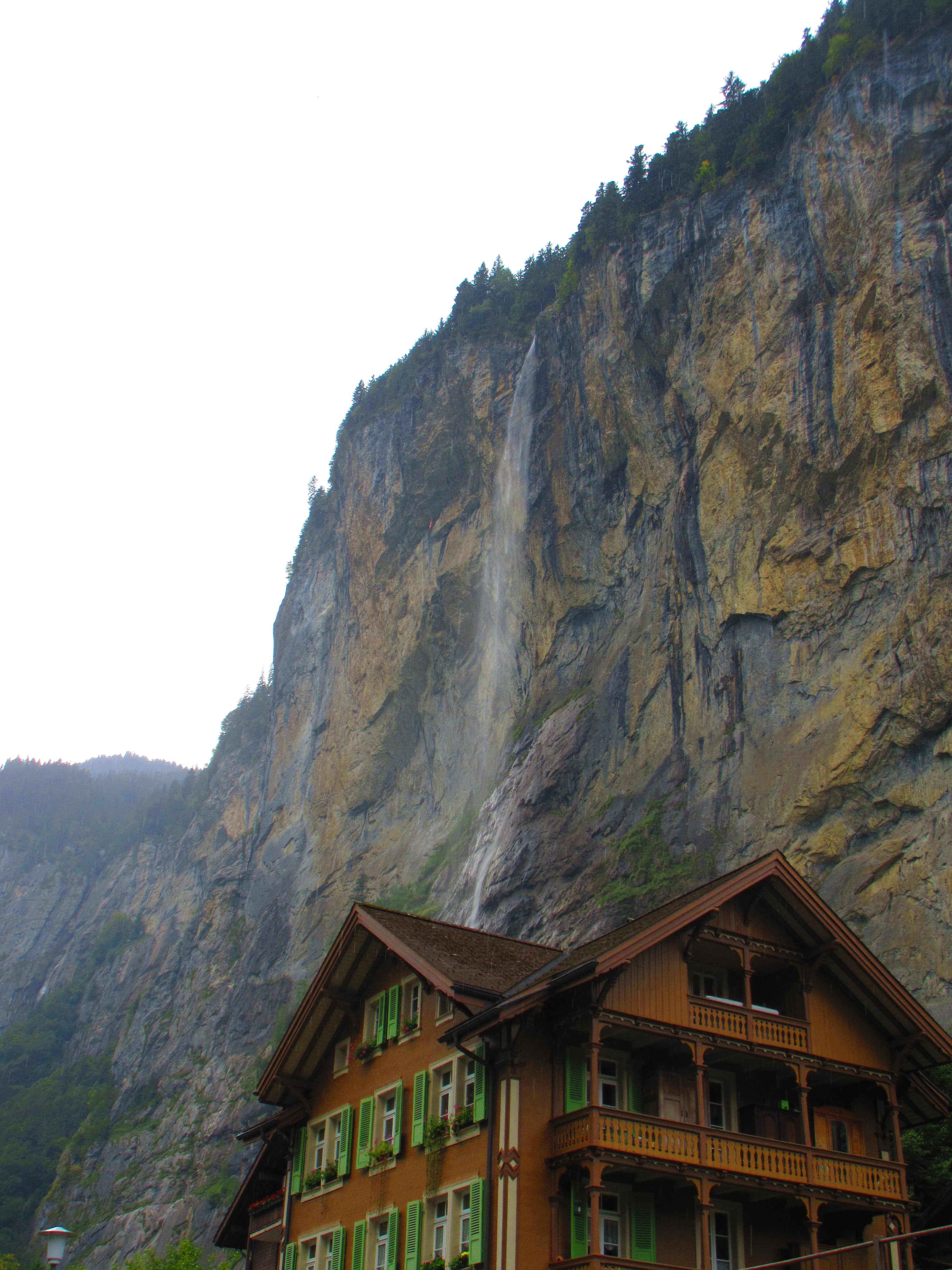 View of a small waterfall falling from a dramatic cliffside on a cloudy day