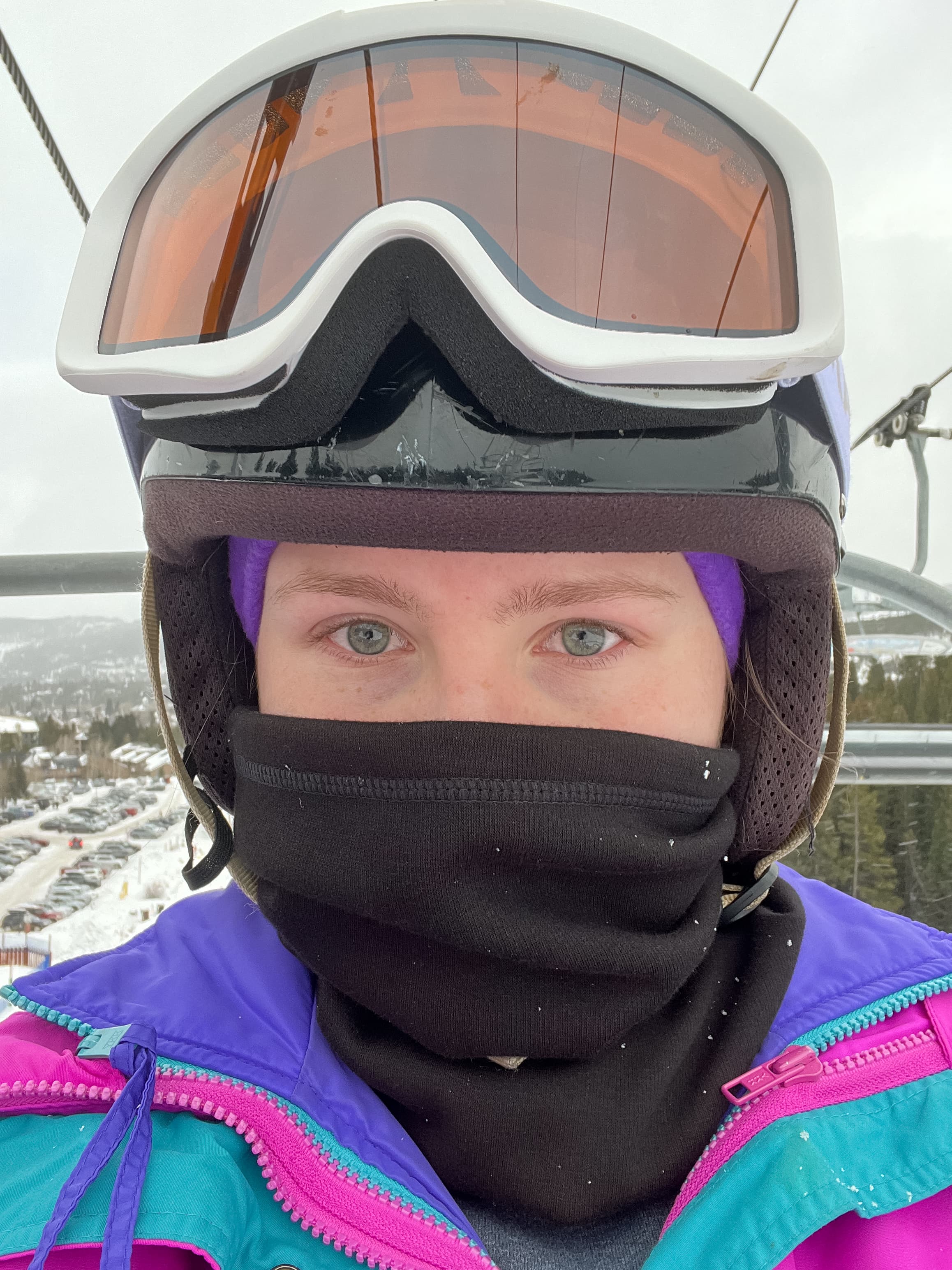 Blair on a ski lift wearing a jacket and goggles during the daytime.