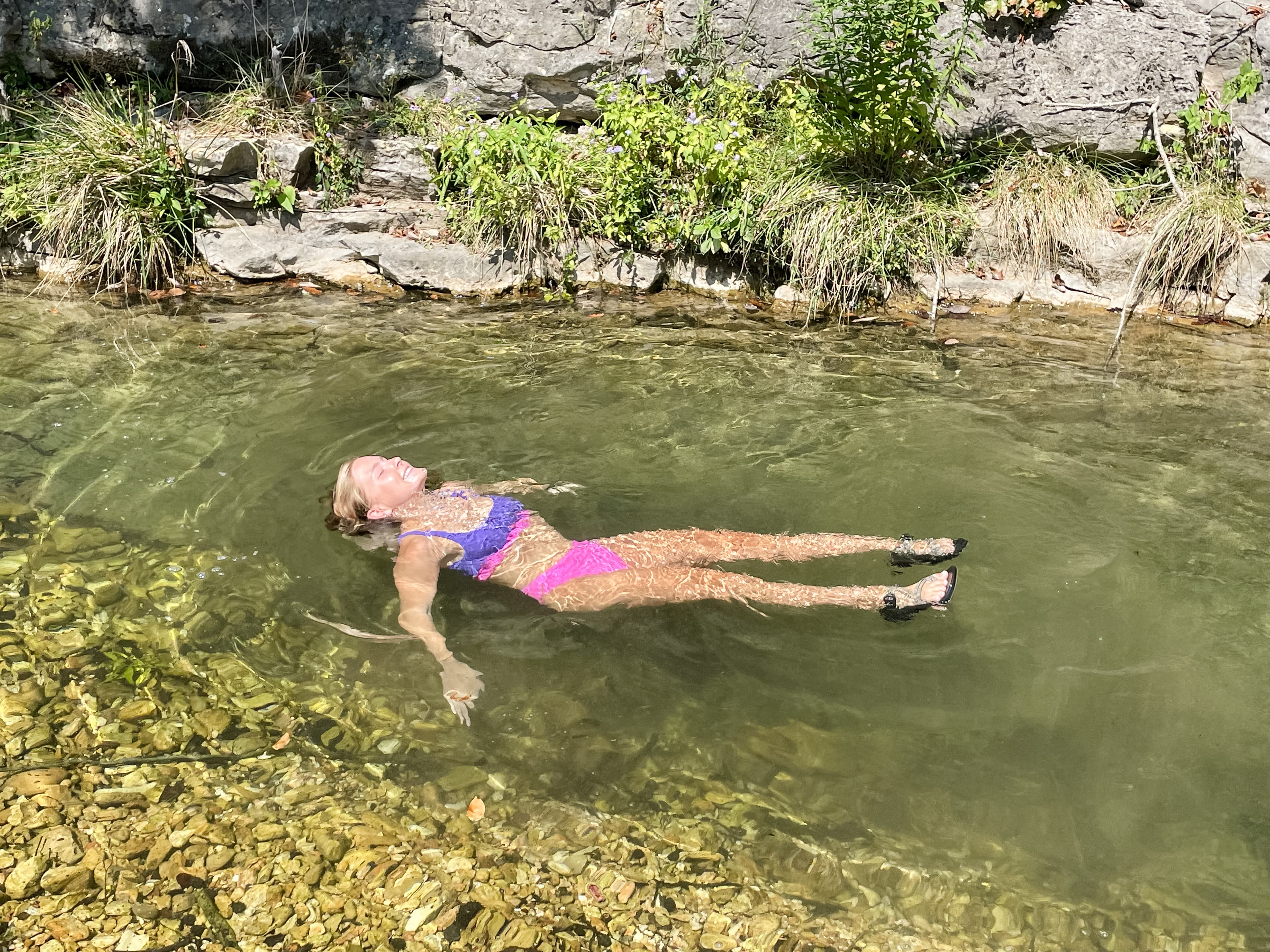 Blair laid back in a pond in nature during the daytime.