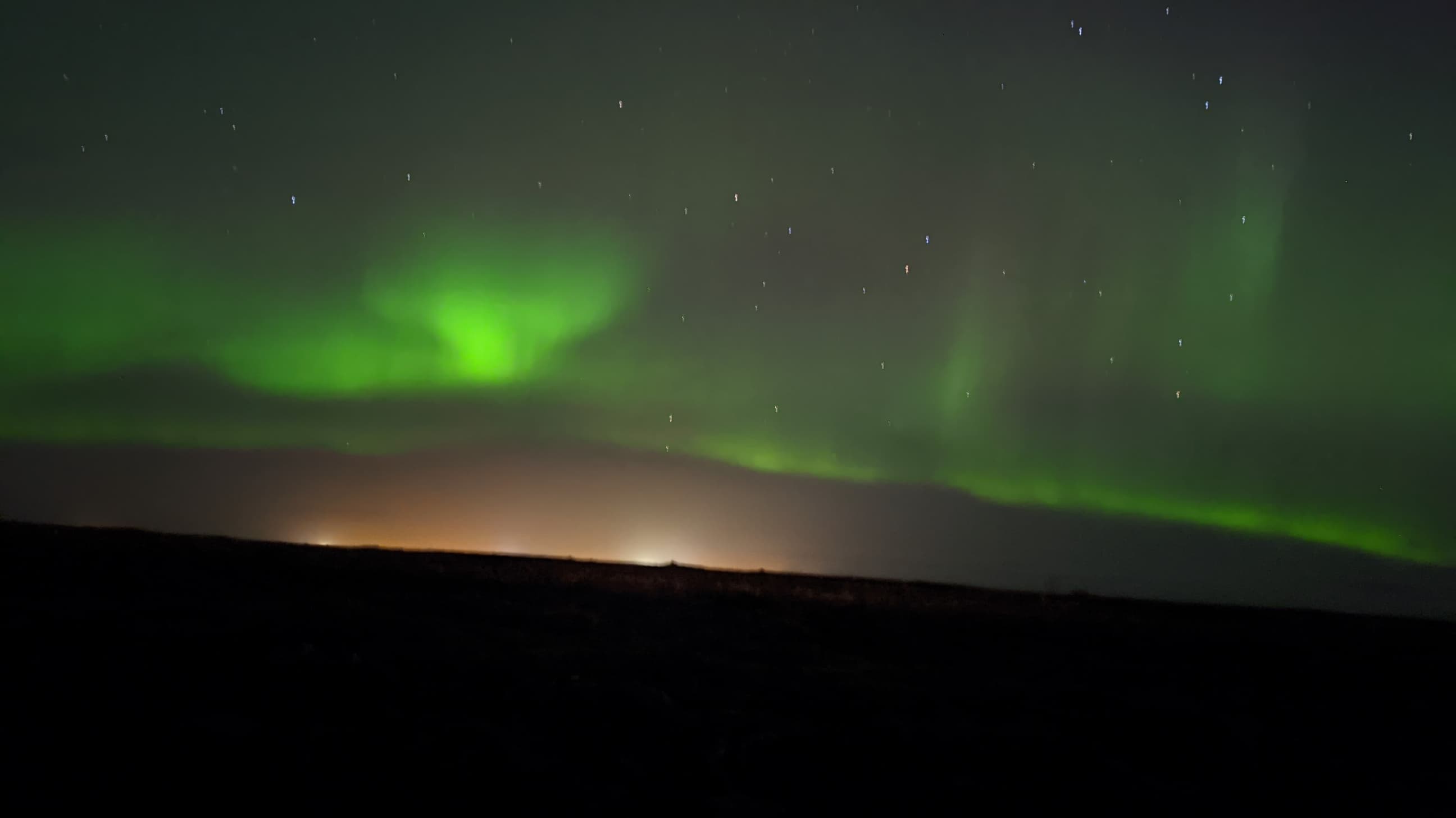 View of the aurora borealis in green light amidst a dark night sky