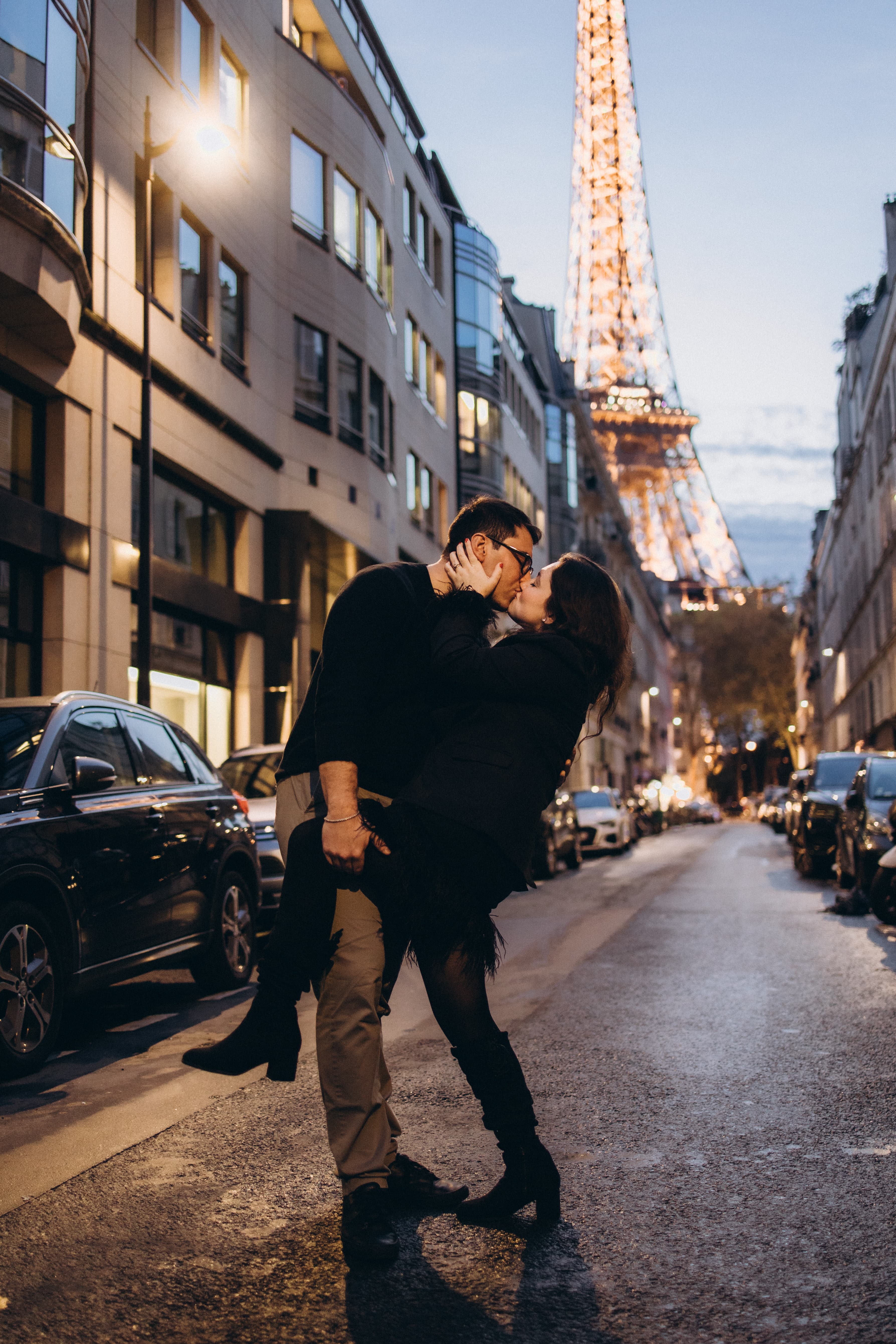 Advisor and partner embracing on the street with the Eiffel Tower lit up at night in the background