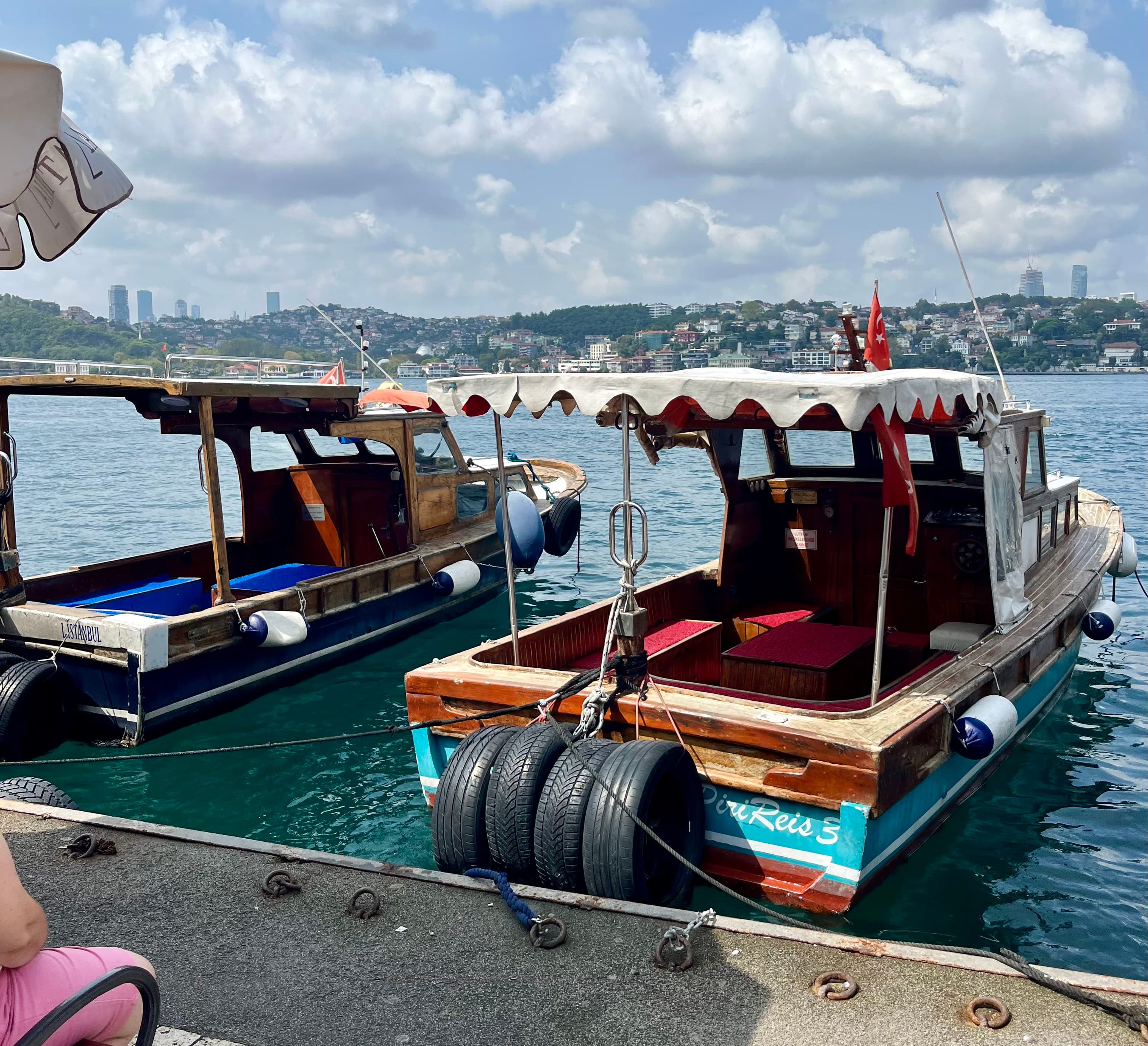 A woman seated on a dock, surrounded by two boats, enjoying a serene moment by the water
