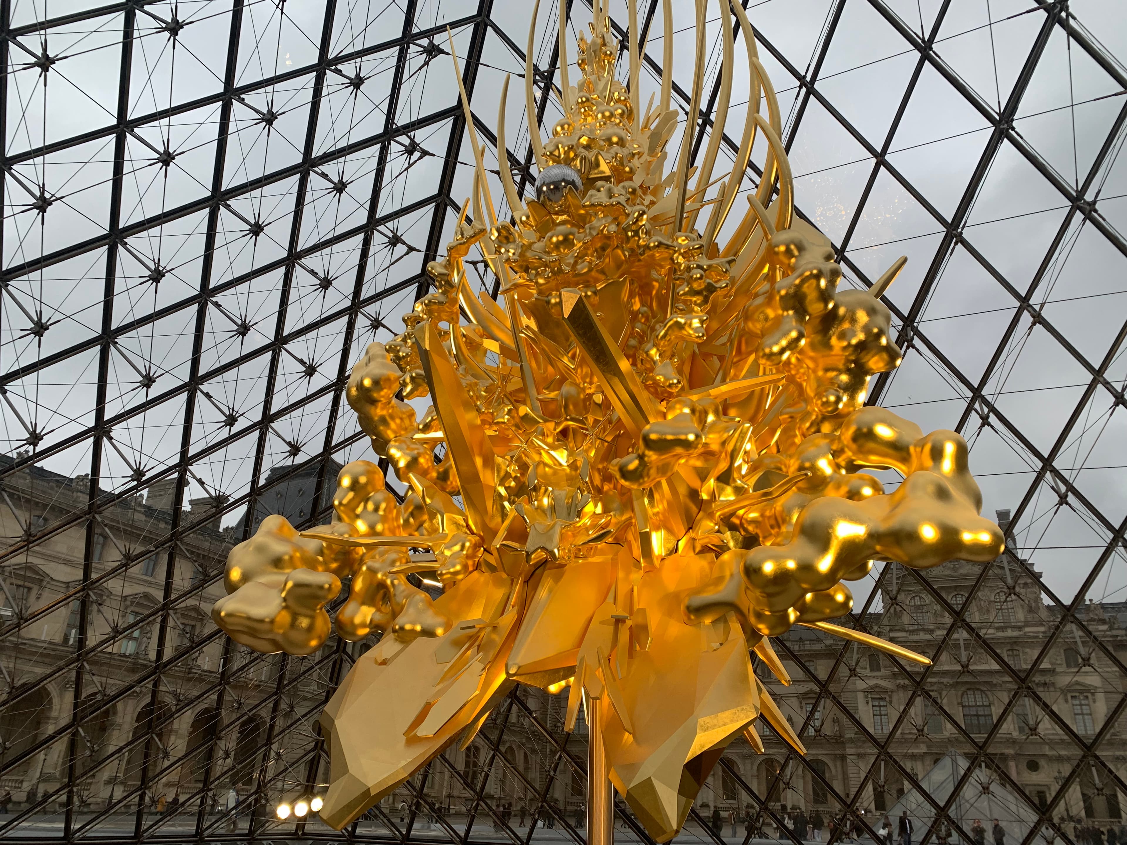 View of a large golden chandelier of a modern design inside a glass structure
