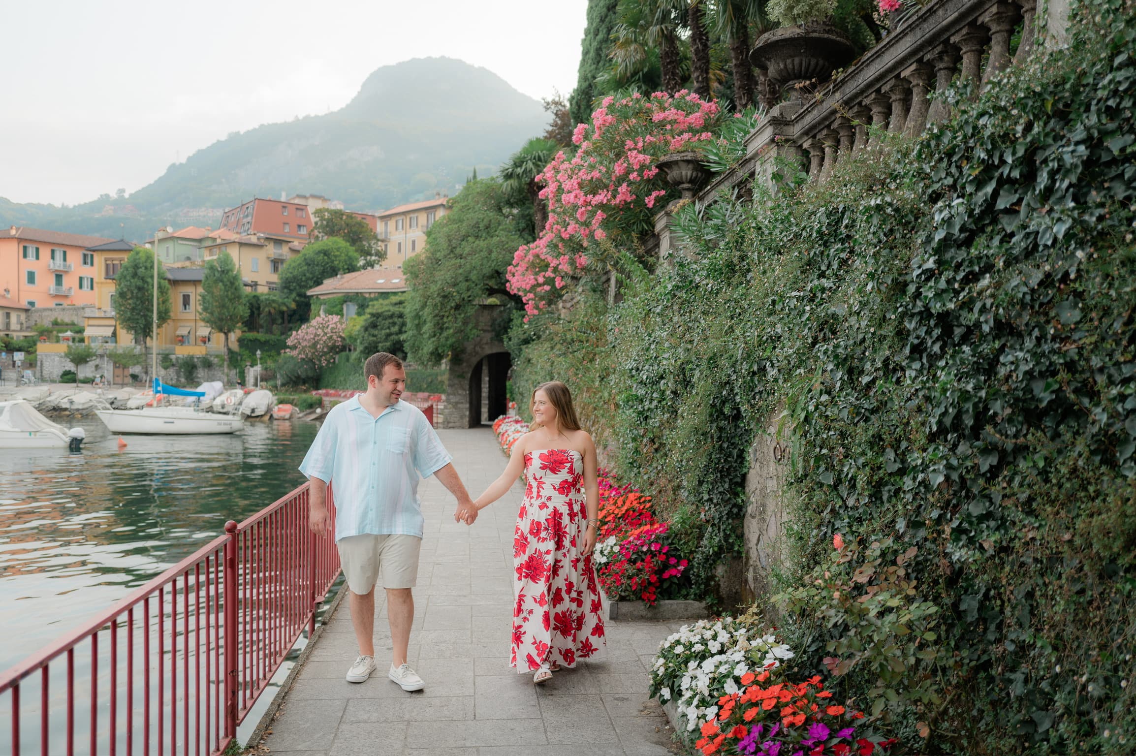 Advisor and husband walking hand in hand on a promenade lined with plants by the sea