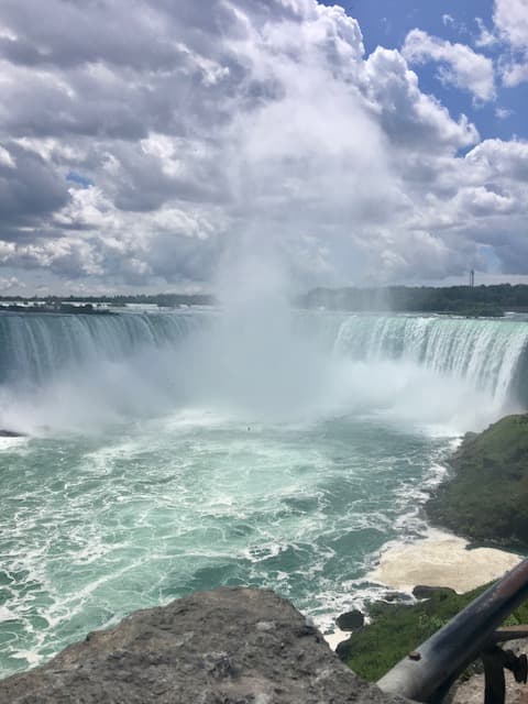 View of a massive waterfall and pool below as seen from above on a sunny day