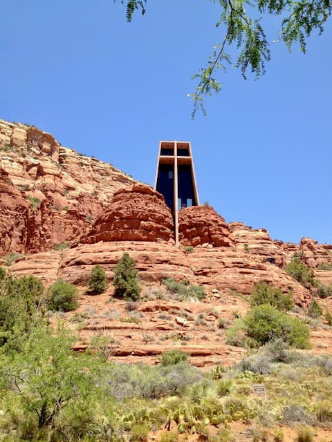 View of a modern structure built on top of a red rock formation under clear skies