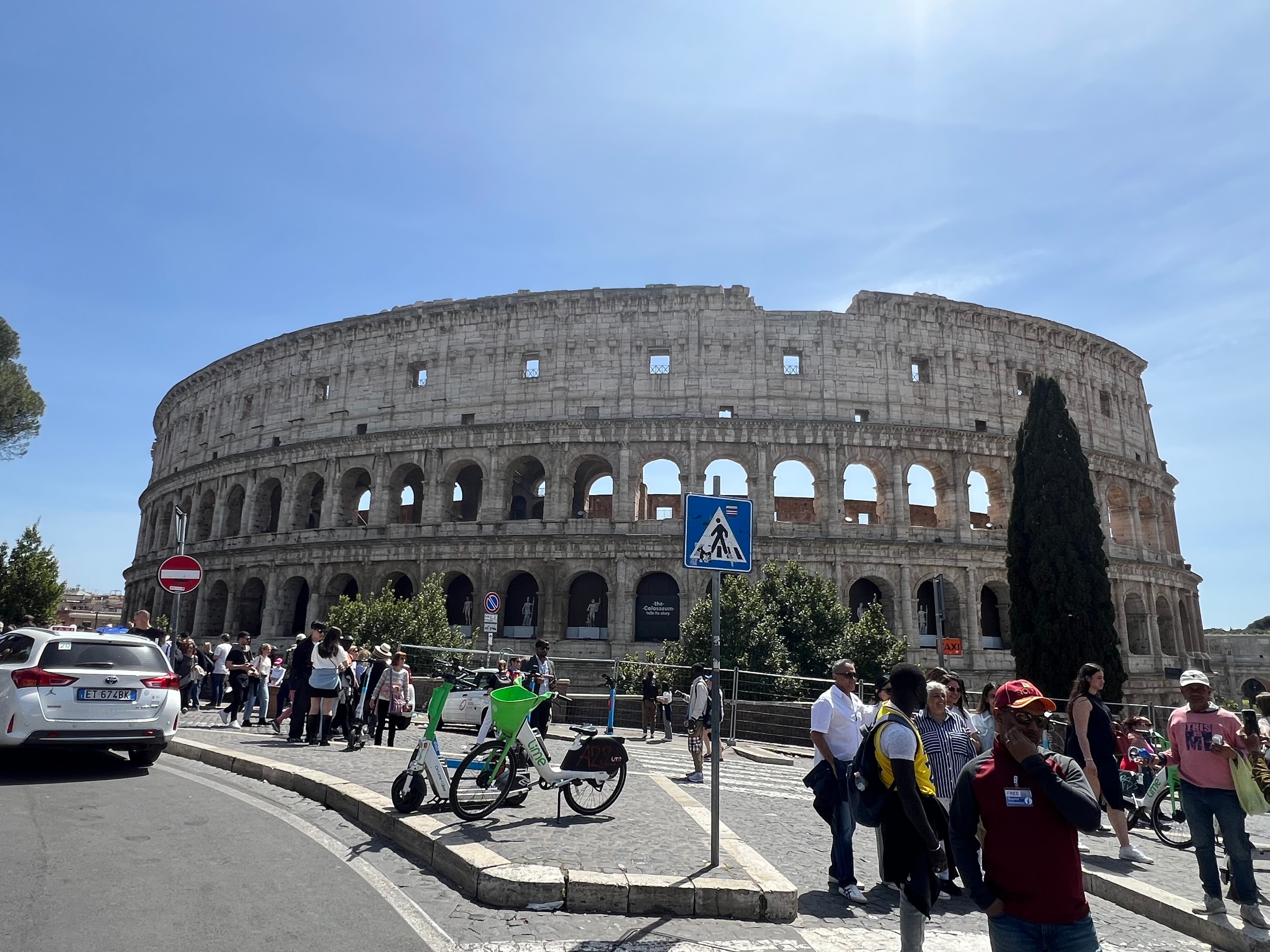View of the Colosseum and surrounding pedestrians on a clear day in Rome