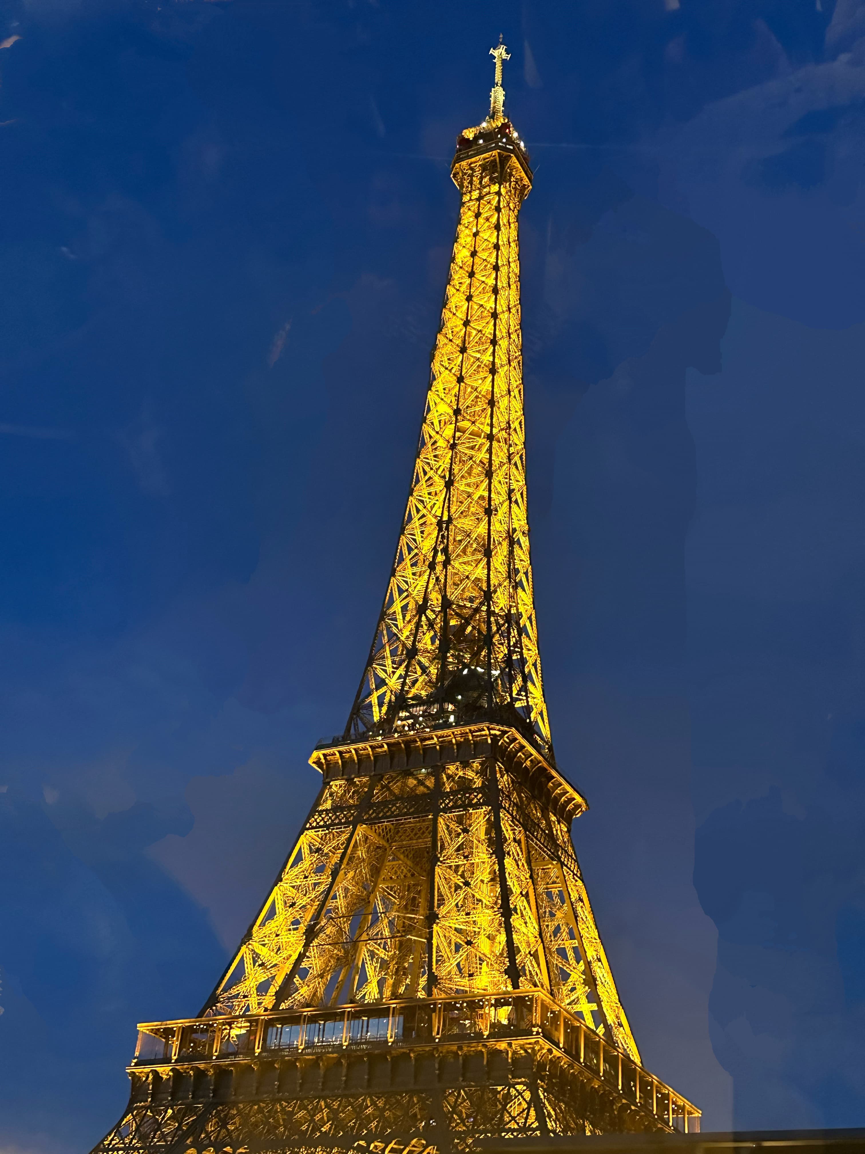 View of the Eiffel Tower lit up at night against dark blue skies