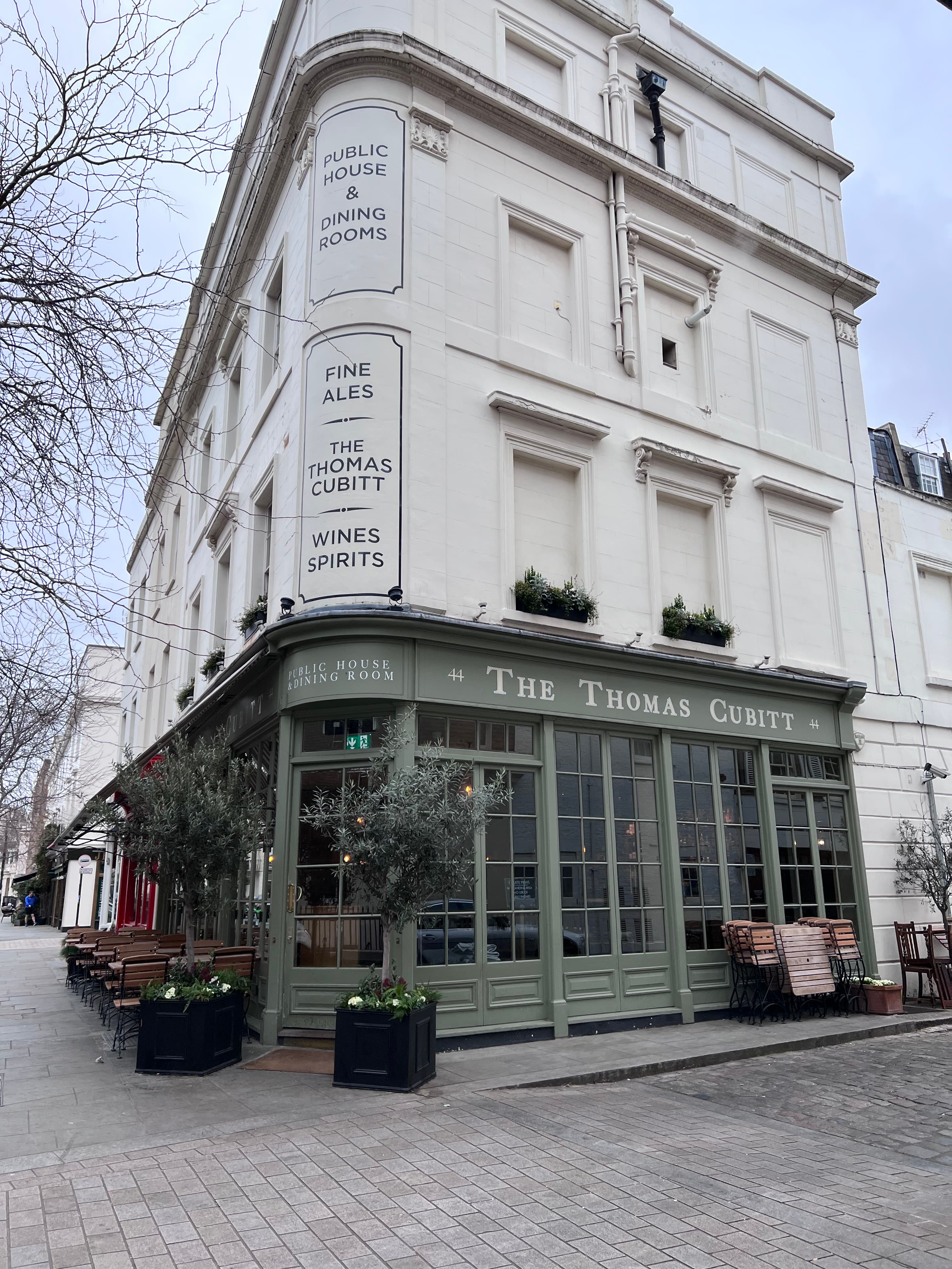 View of a corner building with green pub on the ground floor on a cloudy day